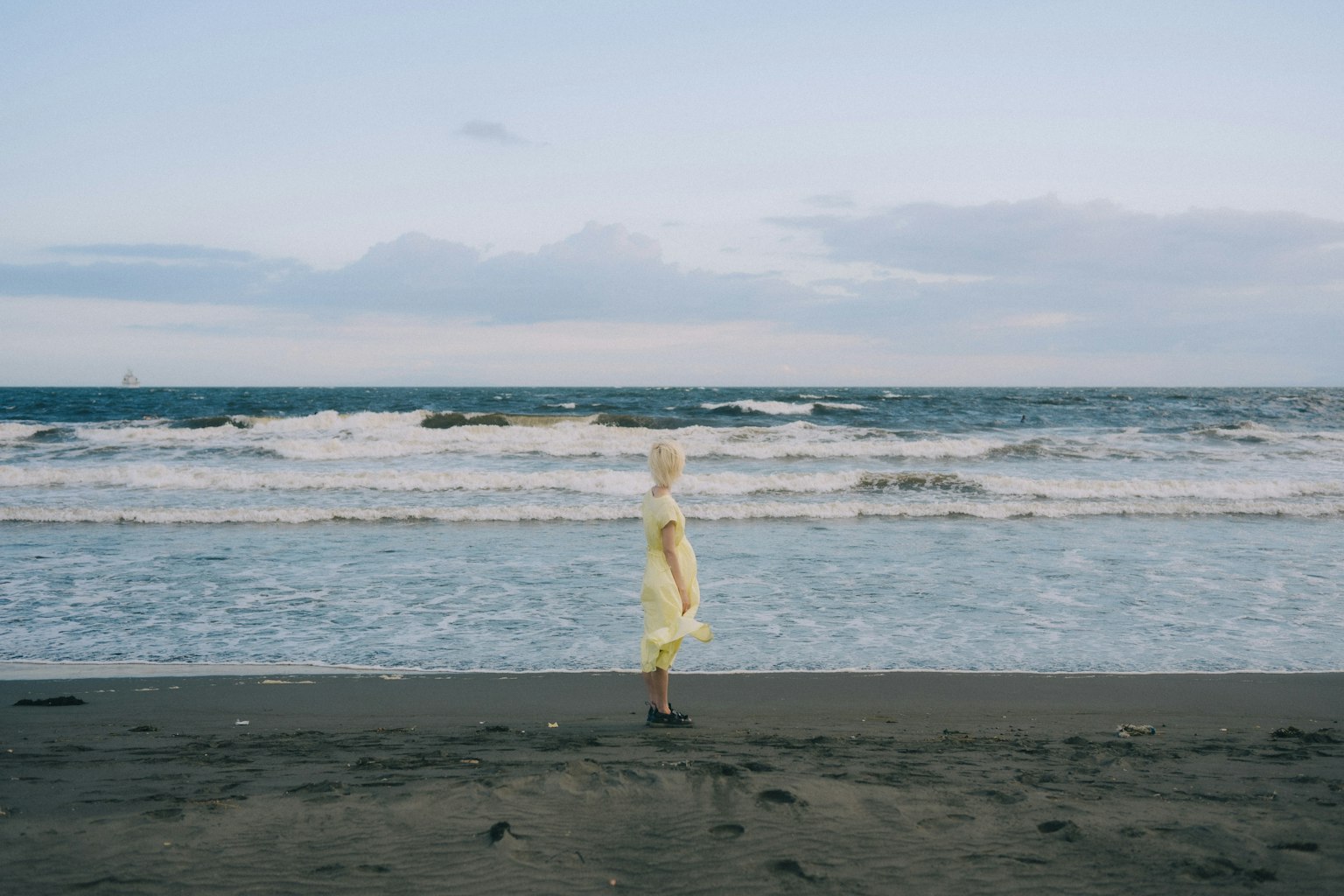 Silhouette di una persona in abito giallo che sta sulla spiaggia