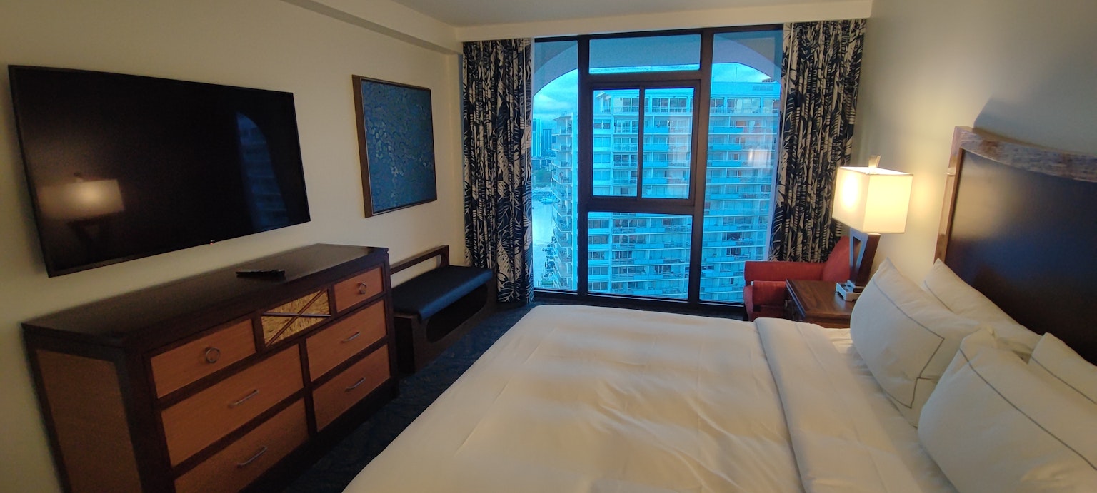 Brightly colored modern hotel room featuring a TV and bed with a view through the window