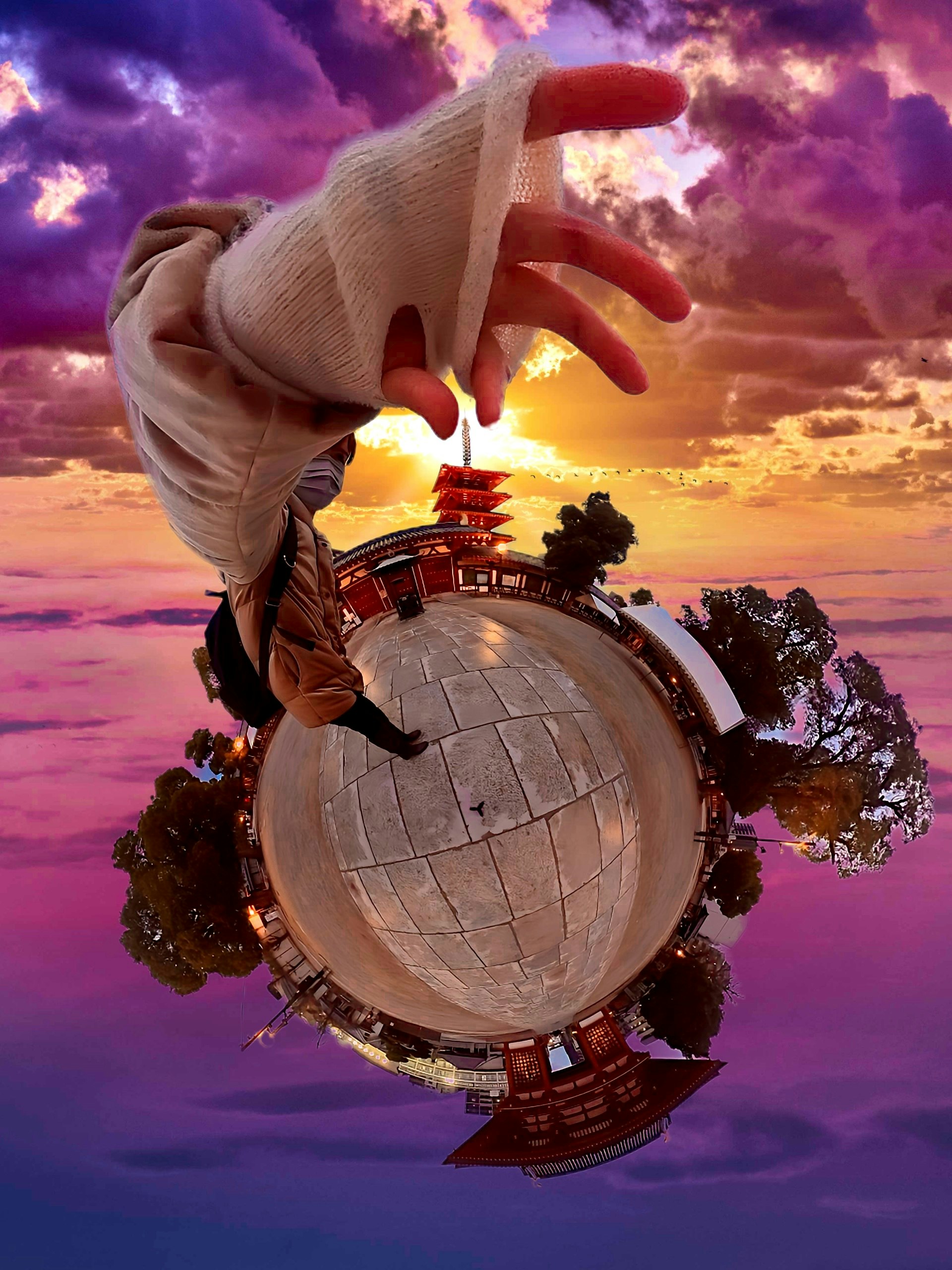 gloved hand holding a globe in a fantasy sunset sky composite