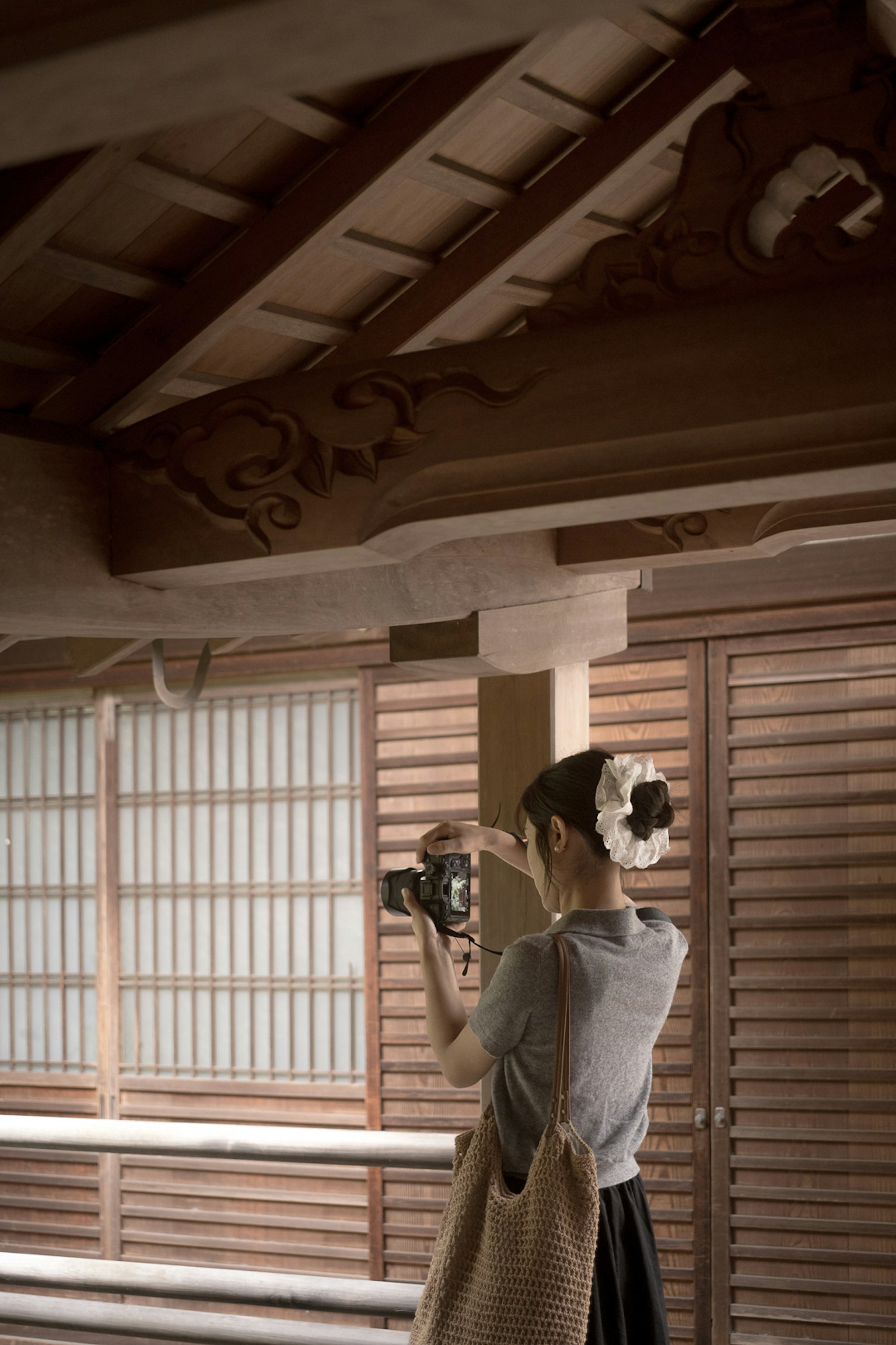 Seorang wanita mengambil foto di dalam ruangan tradisional Jepang dengan balok kayu