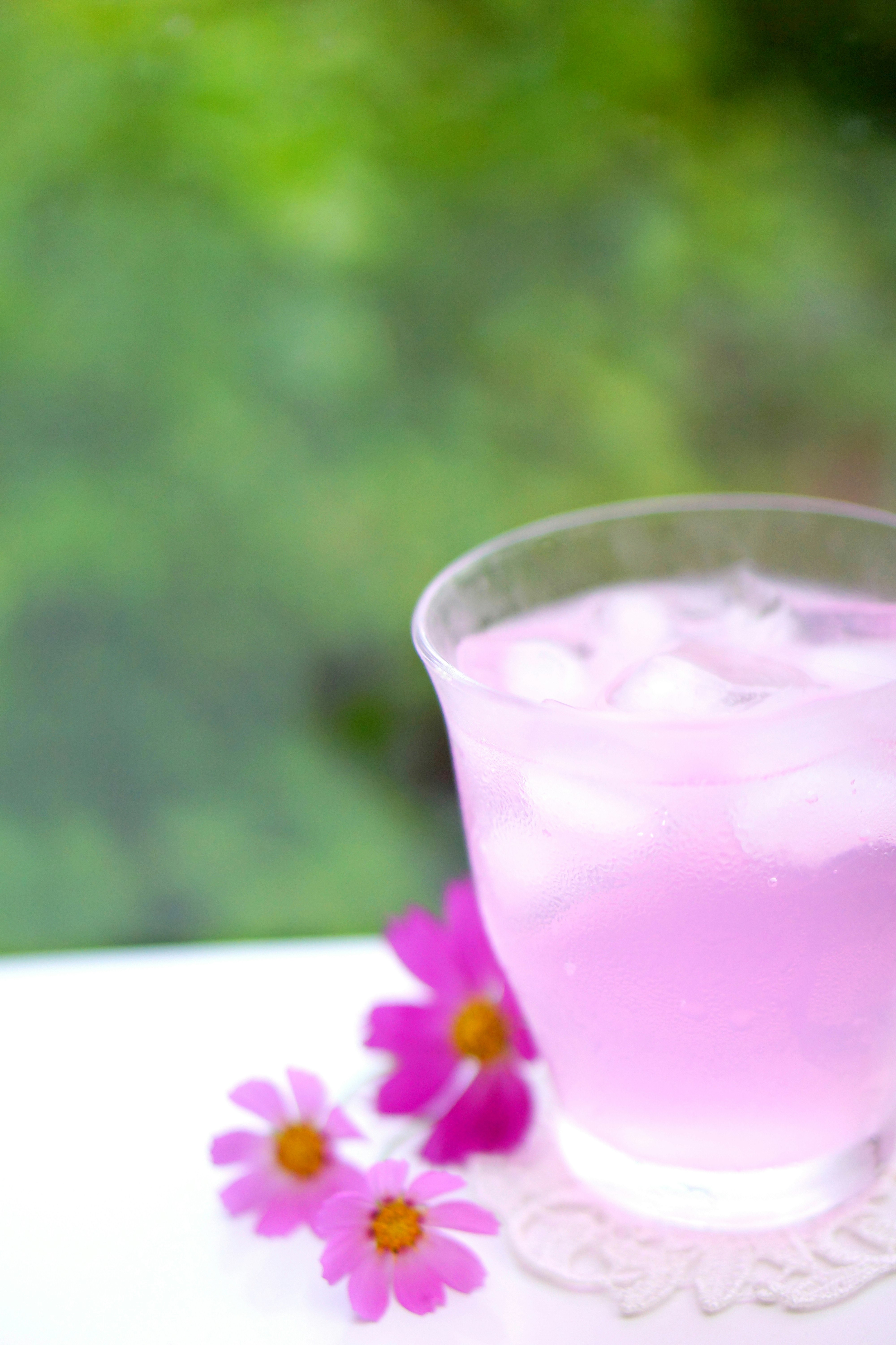 ly đồ uống màu hồng với hoa tím trên bàn