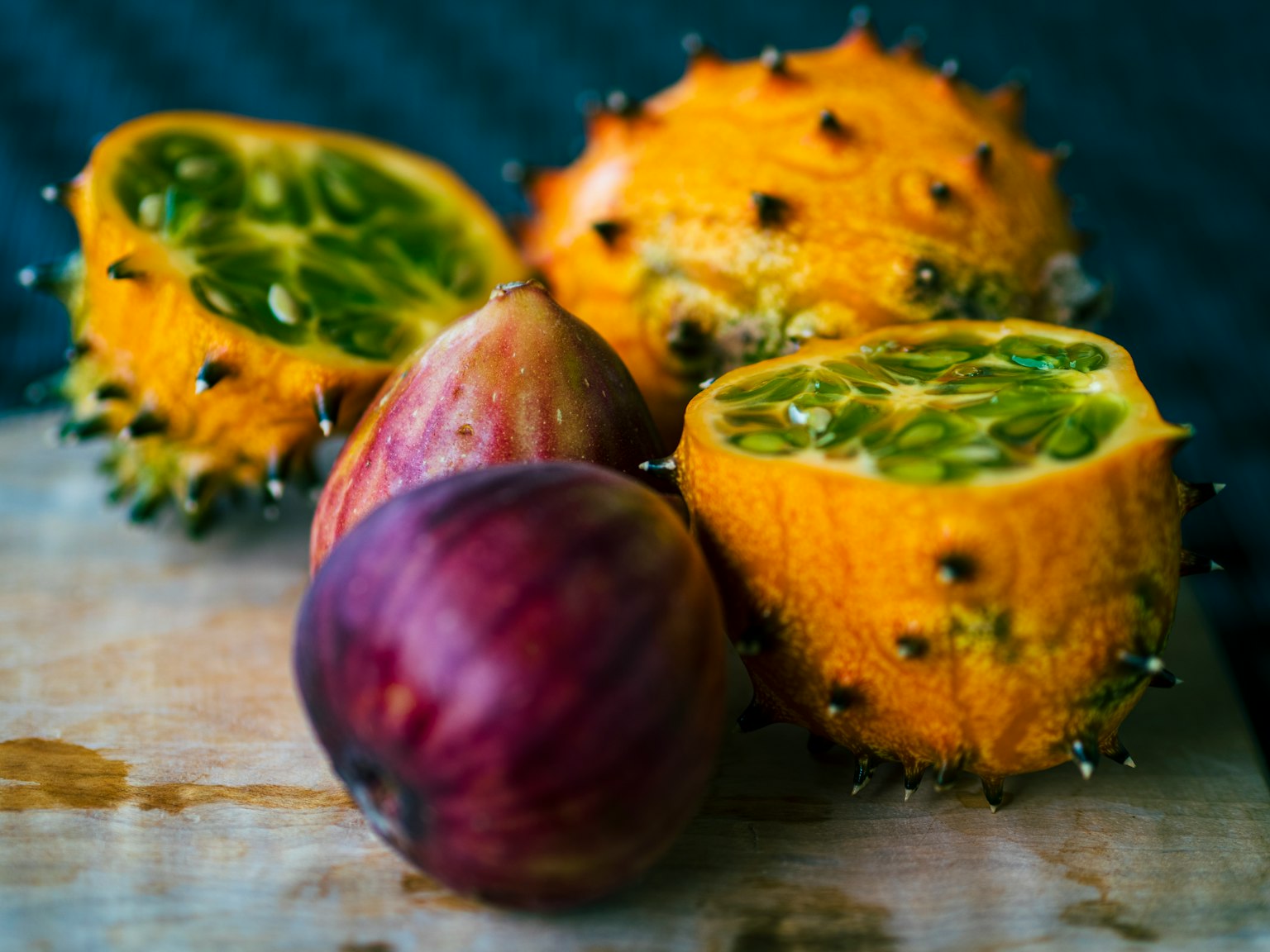 Fruta espinosa amarilla y higo morado sobre una tabla de madera