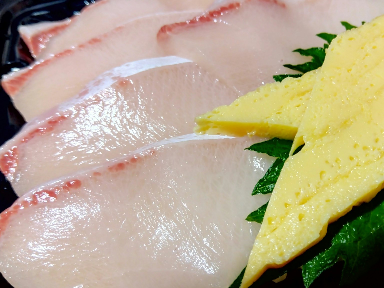 Rebanadas de sashimi fresco con un lado de tamagoyaki