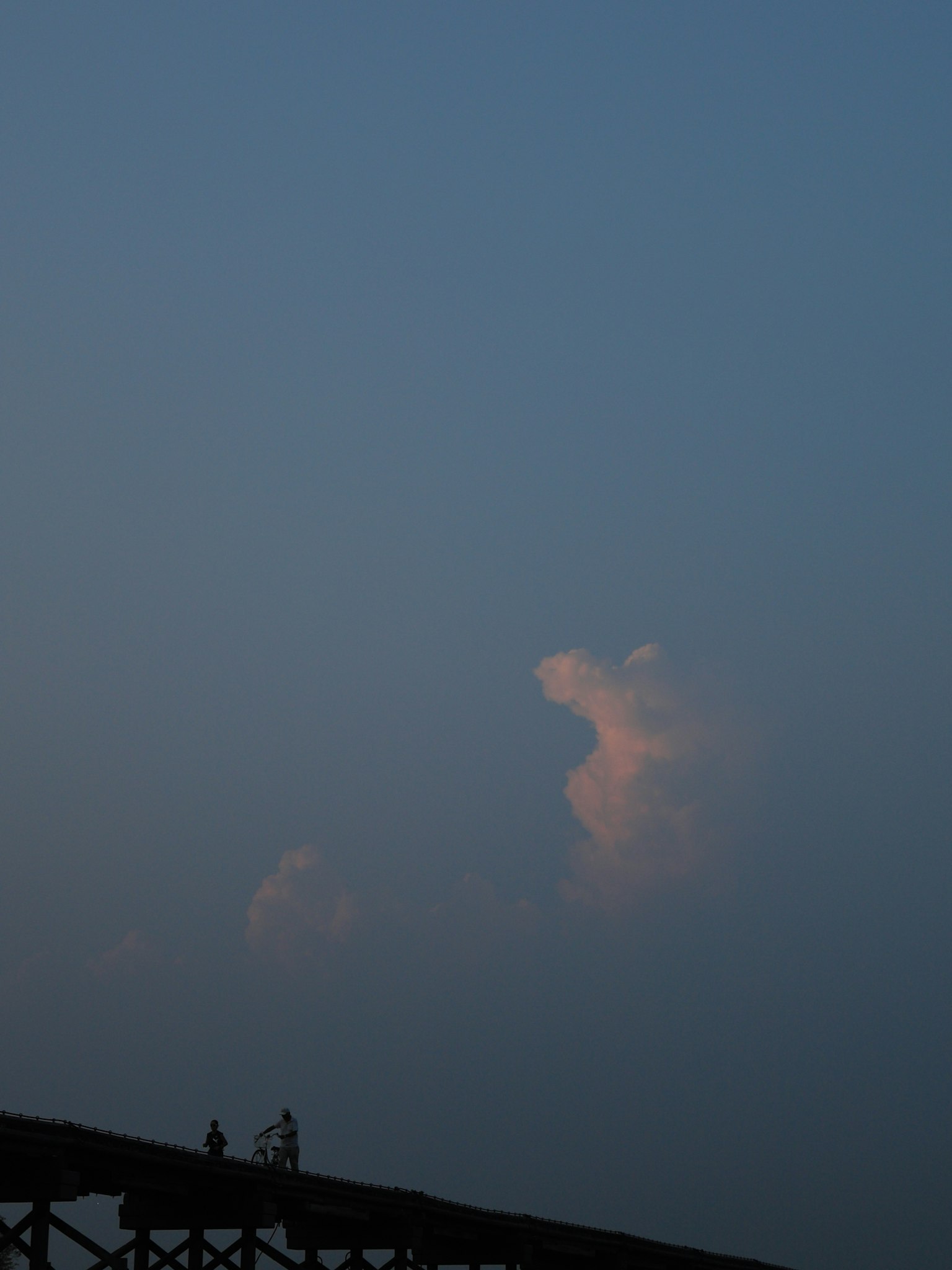 Faint clouds in a blue sky with silhouettes of people
