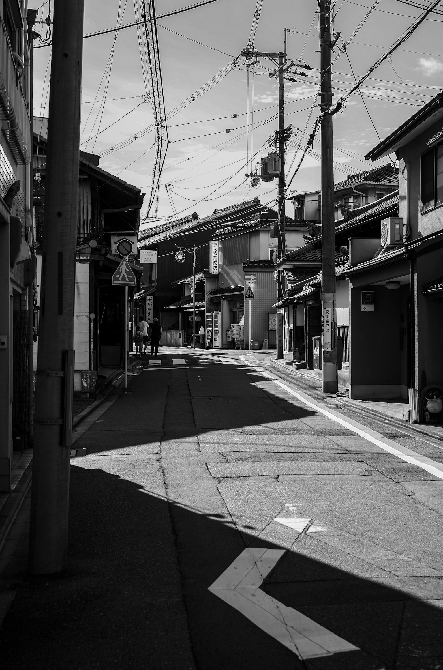 Narrow street with a bend featuring old buildings in black and white