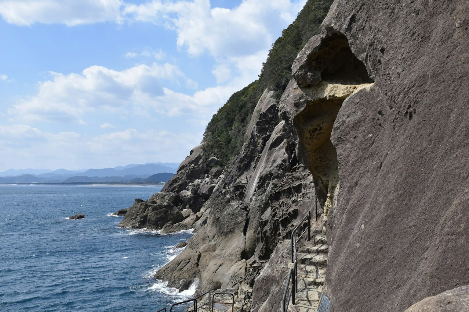 Staircase along a rocky cliff near the sea with green vegetation