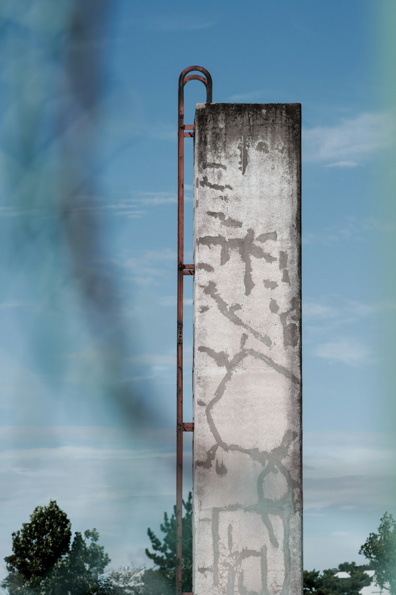Pared de concreto con una escalera roja bajo un cielo azul