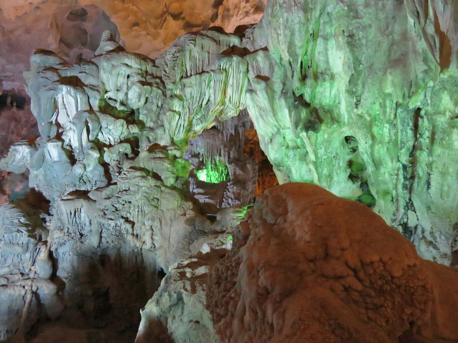 Innere einer Höhle mit Felsformationen und grünen Lichteffekten