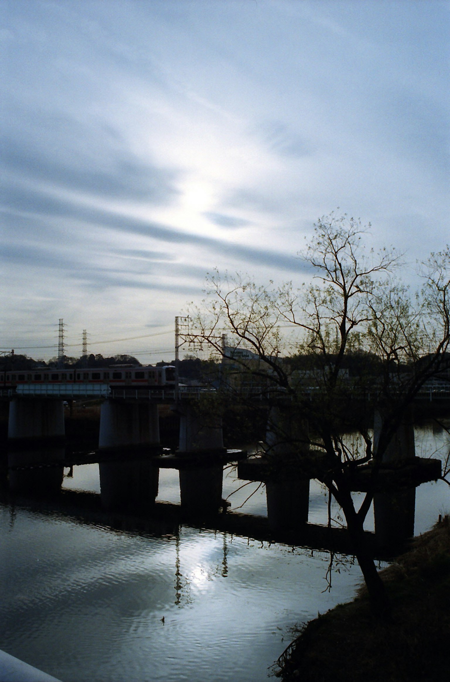 寧靜的河流場景與橋，陰雲密布的天空，反射的水面，冬季樹木