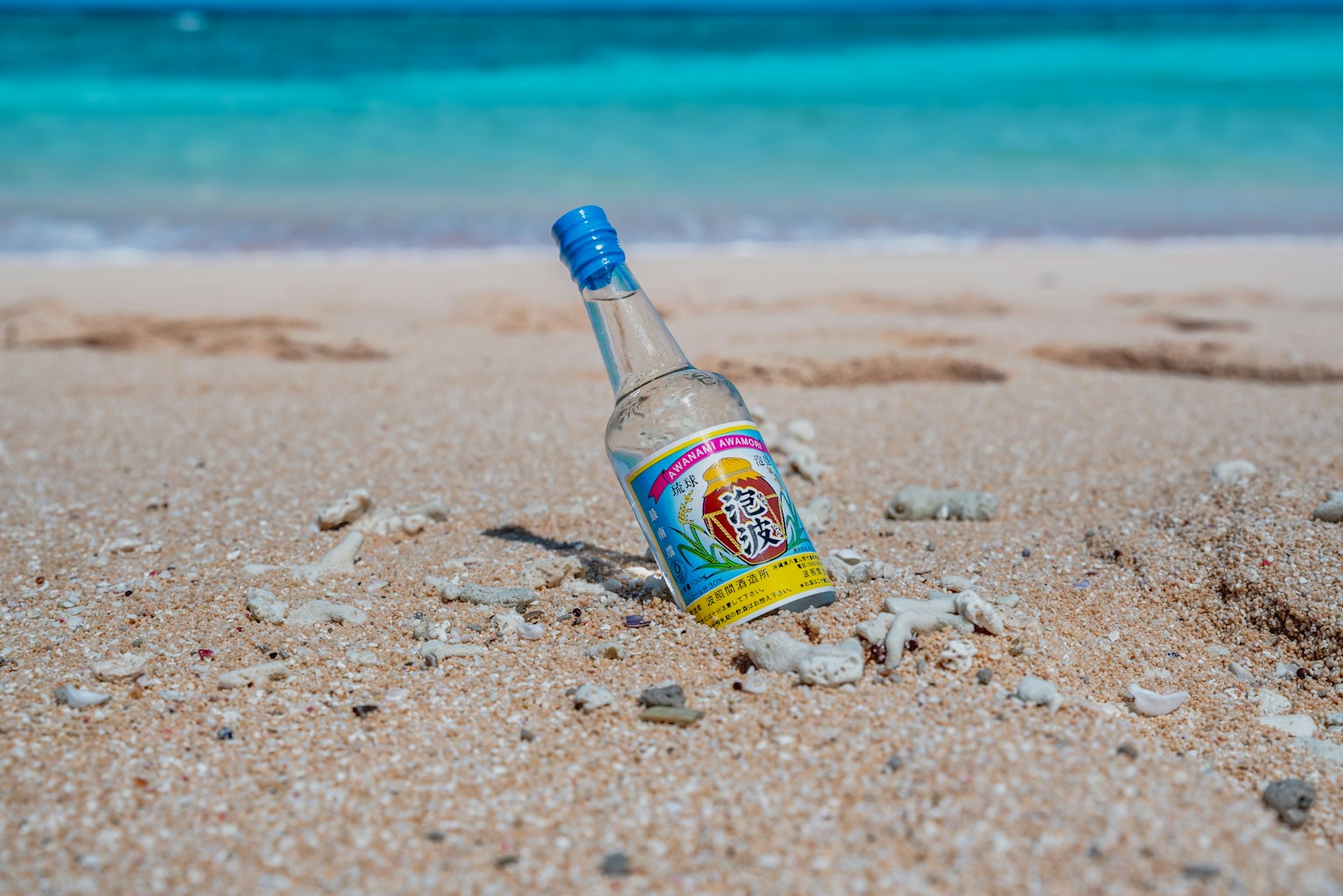 Colorful bottle half-buried in sand on the beach