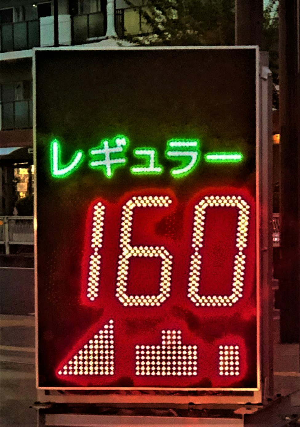 Night street corner with neon “Regular” price sign showing “160”