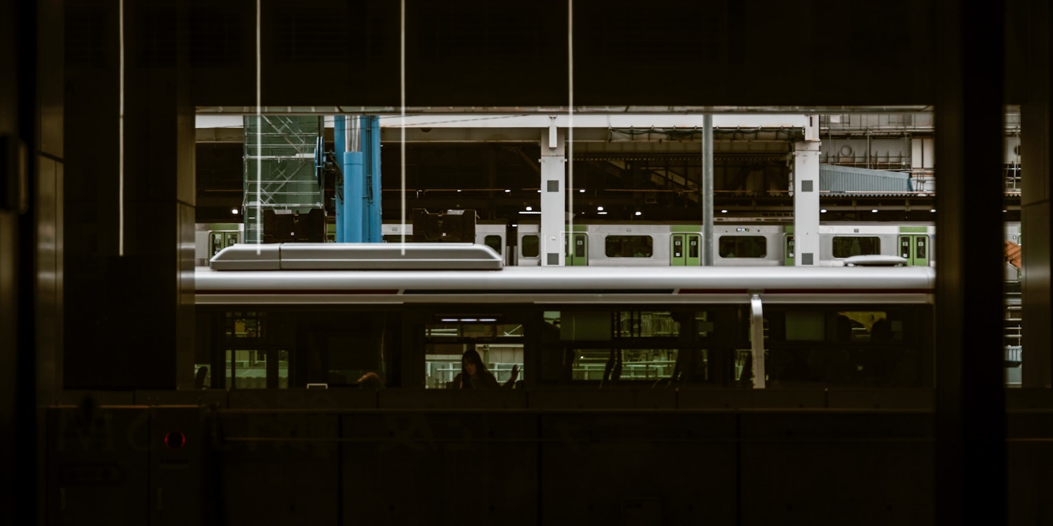 Partial view of a train at a dark station platform with a blue pillar