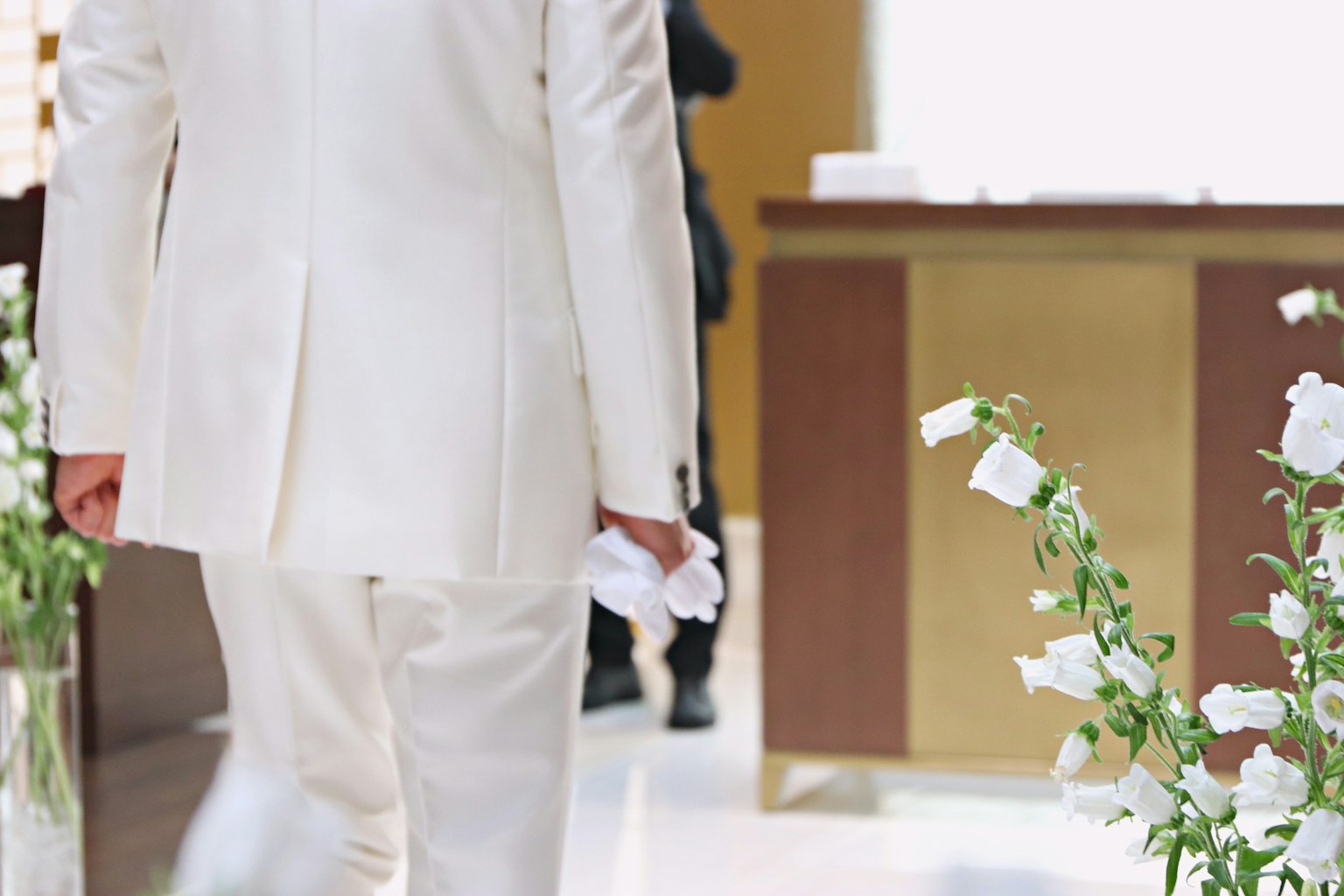 A man in a white suit walking in a floral setting