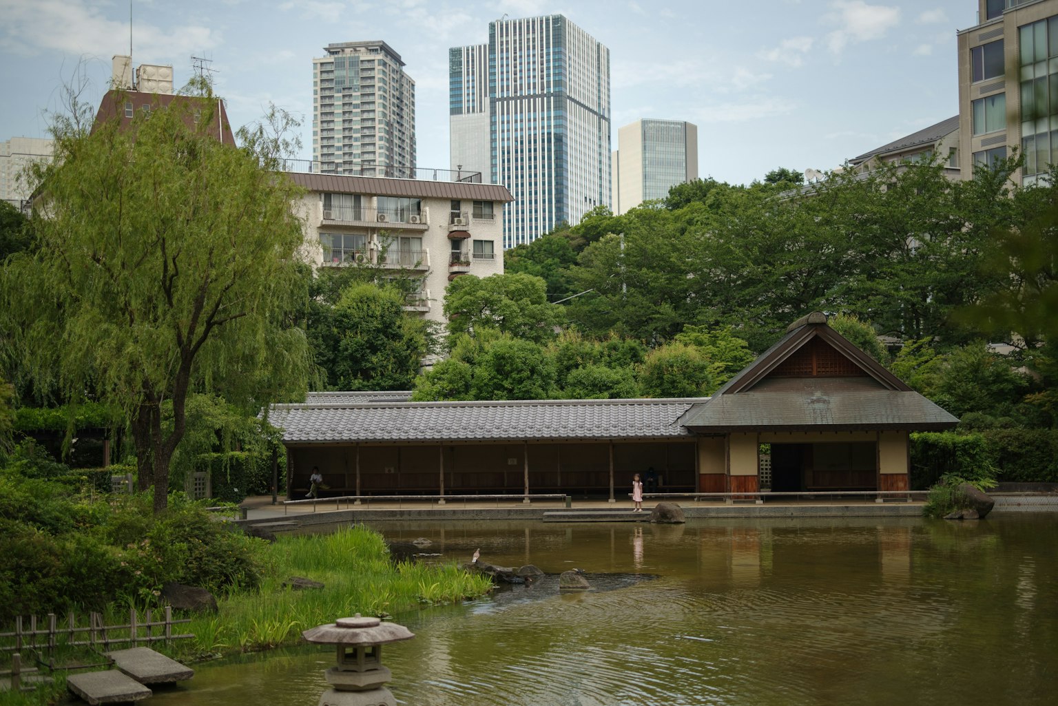 Jardin japonais serein avec une maison de thé traditionnelle au milieu des bâtiments urbains