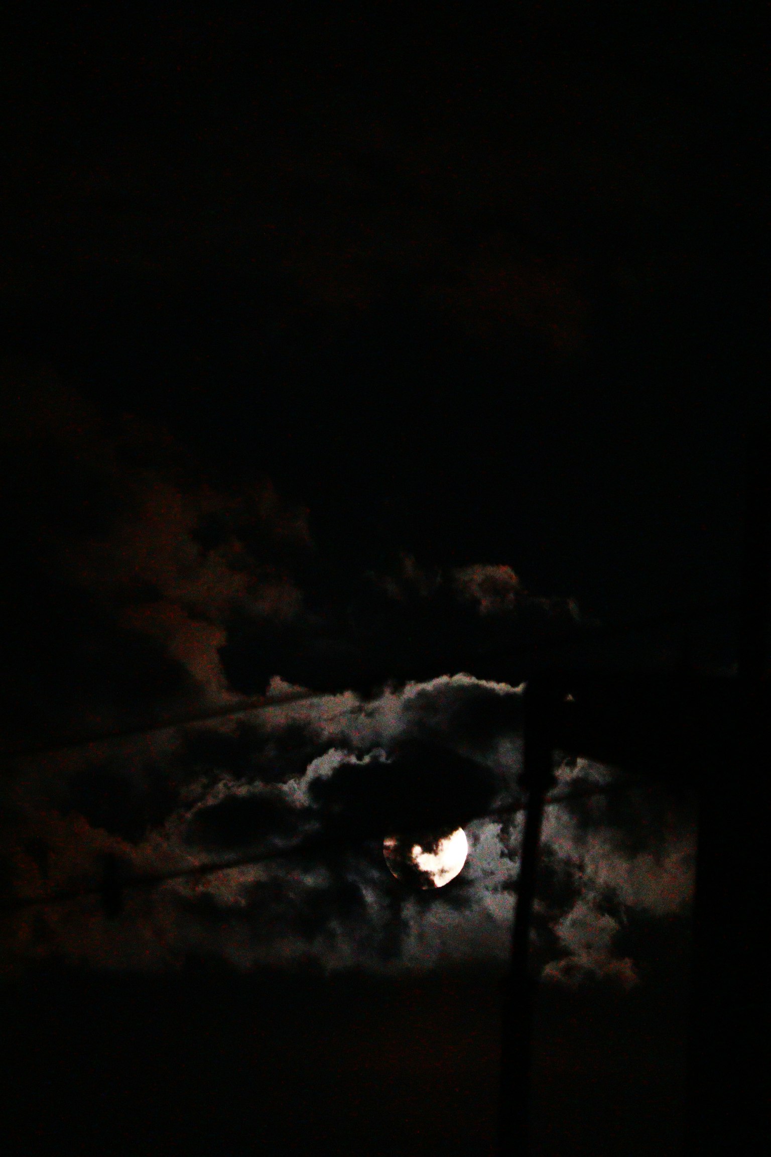 Luna parcialmente oculta por nubes en un cielo oscuro
