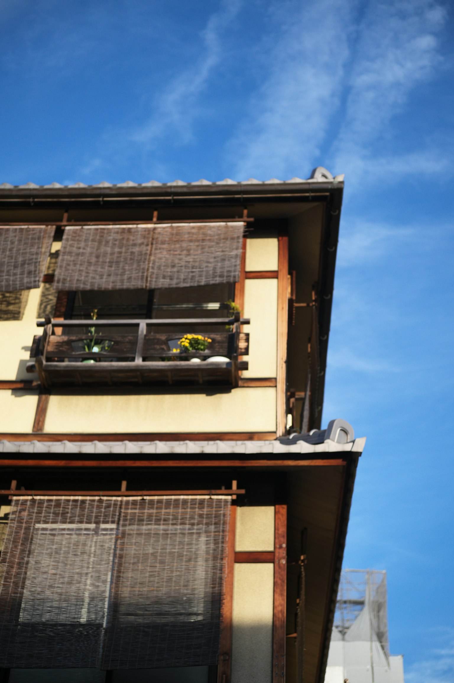 Holzgebäude mit Balkon und Sonnenschutz unter blauem Himmel