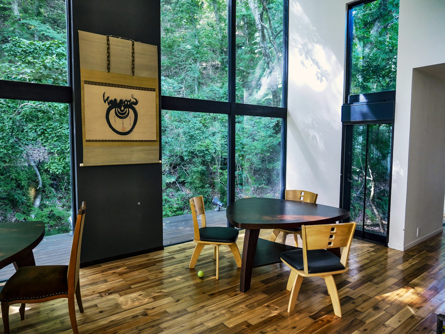 Salle à manger moderne avec de grandes fenêtres donnant sur une verdure luxuriante