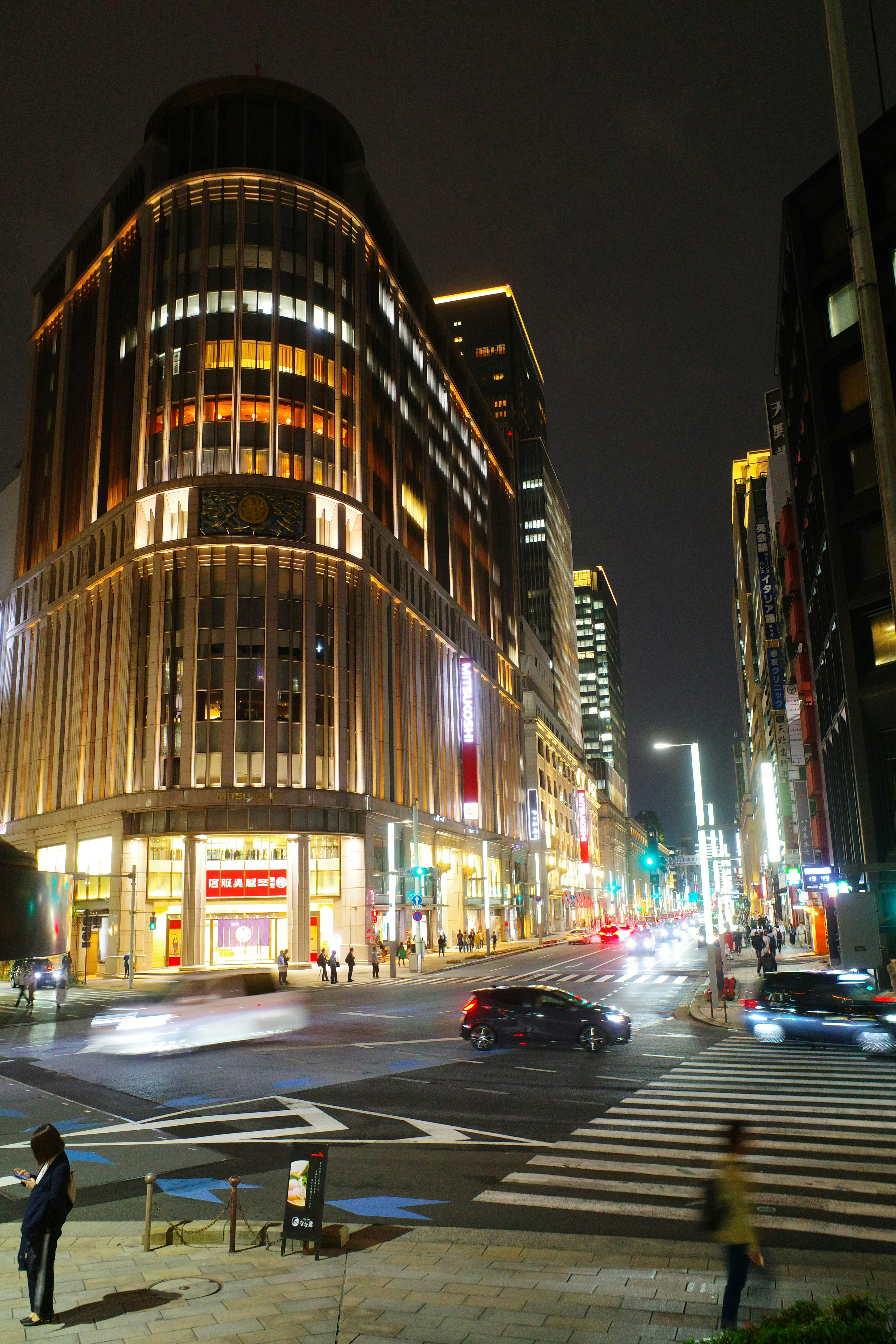 夜の大通りを走る車と高層ビルの街並み
