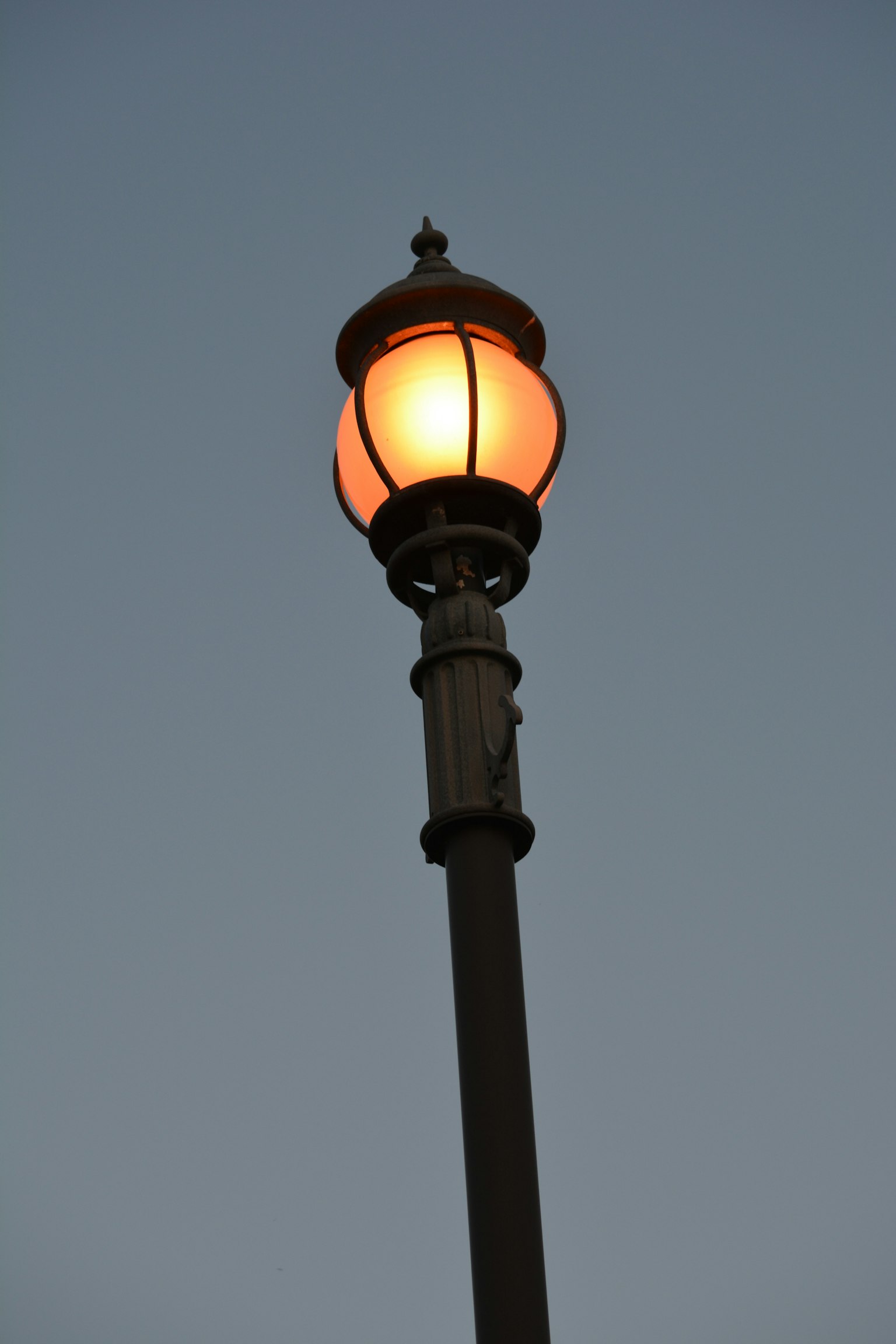 Straßenlaterne, die orangefarbenes Licht bei Dämmerung ausstrahlt