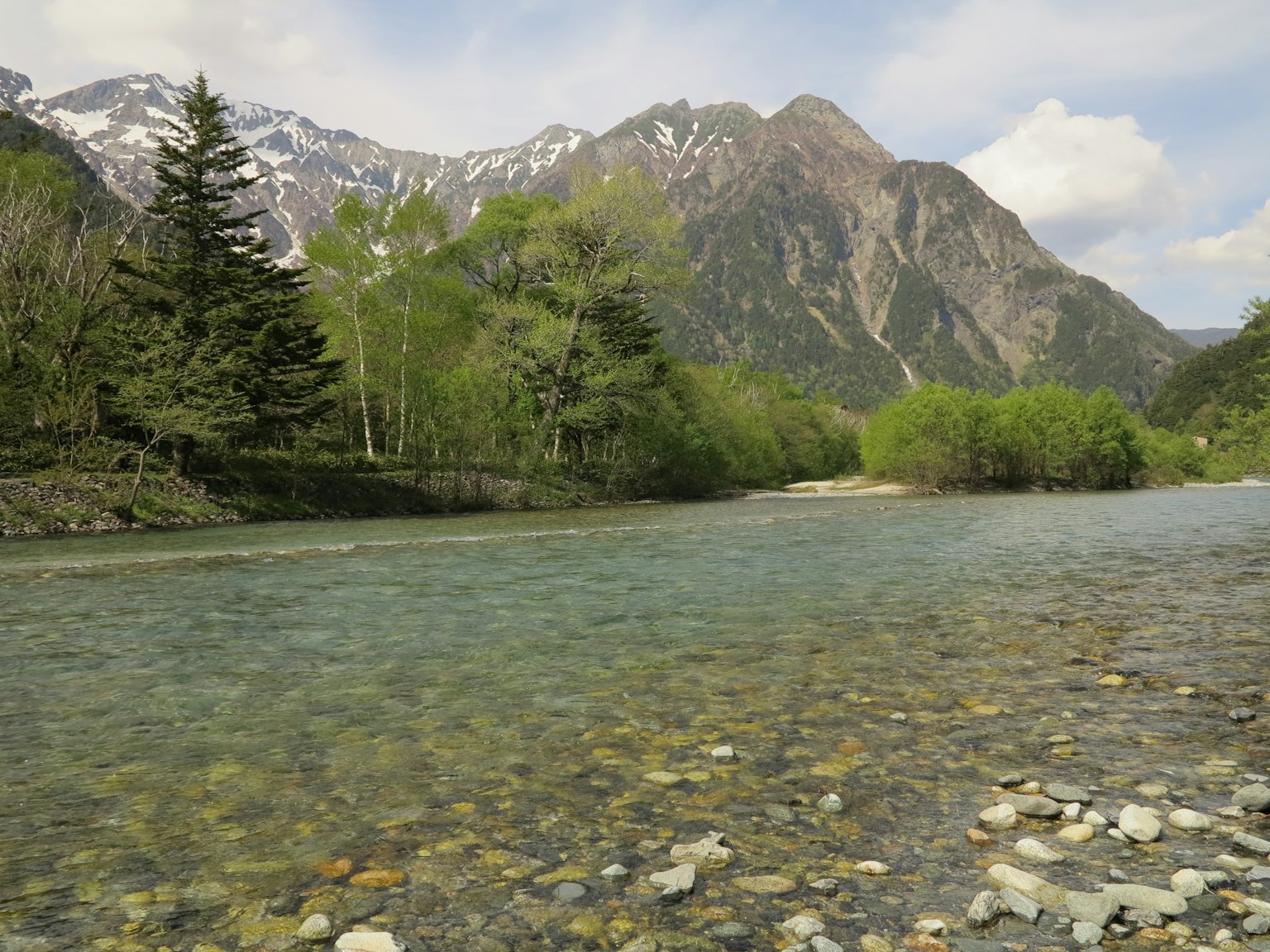 Malerei von einem klaren Fluss umgeben von grünen Bäumen und Bergen
