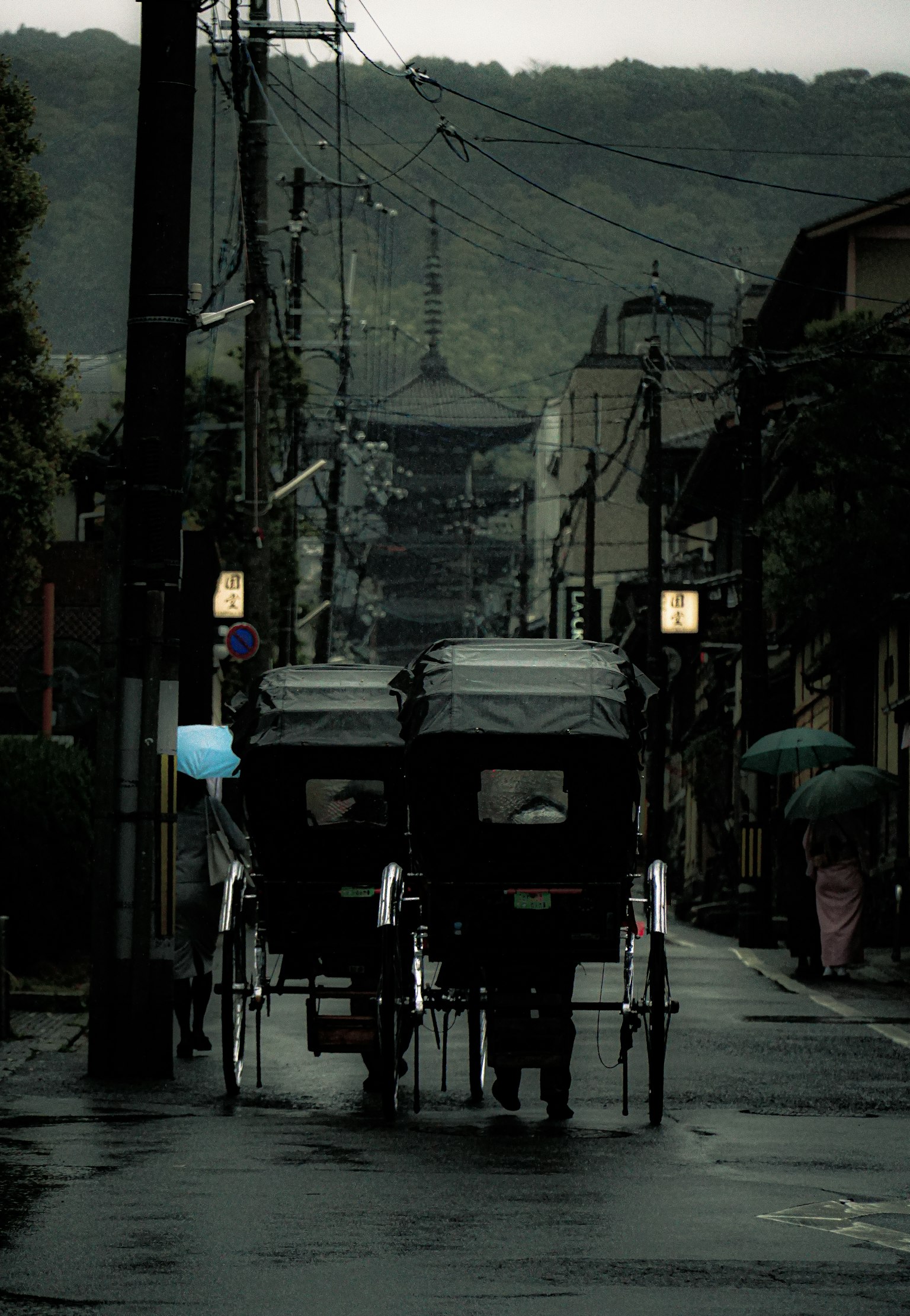 Rickshaws en una calle mojada con edificios antiguos al fondo