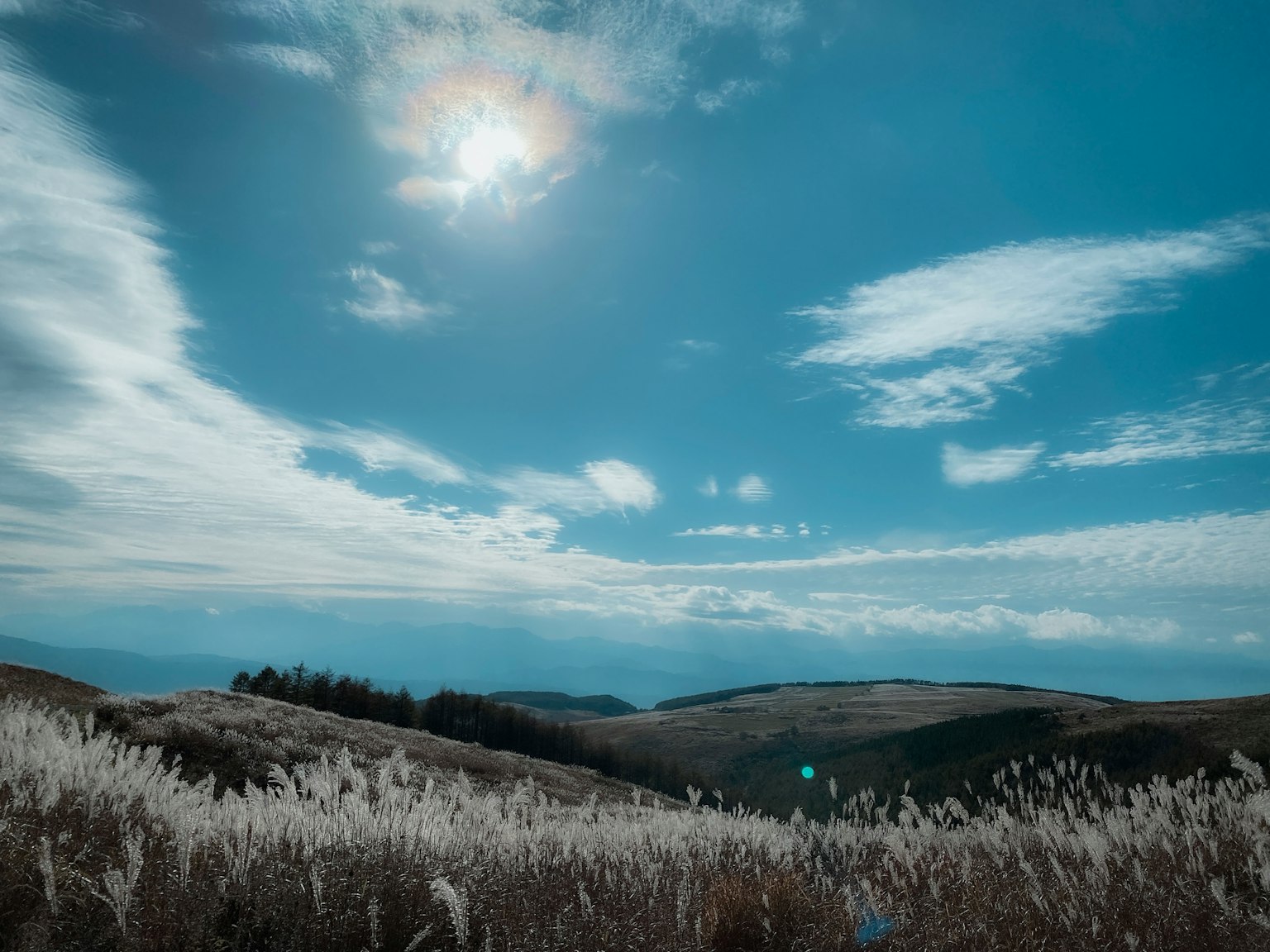 Paysage avec un soleil brillant dans un ciel bleu avec des nuages sur des collines ondulantes