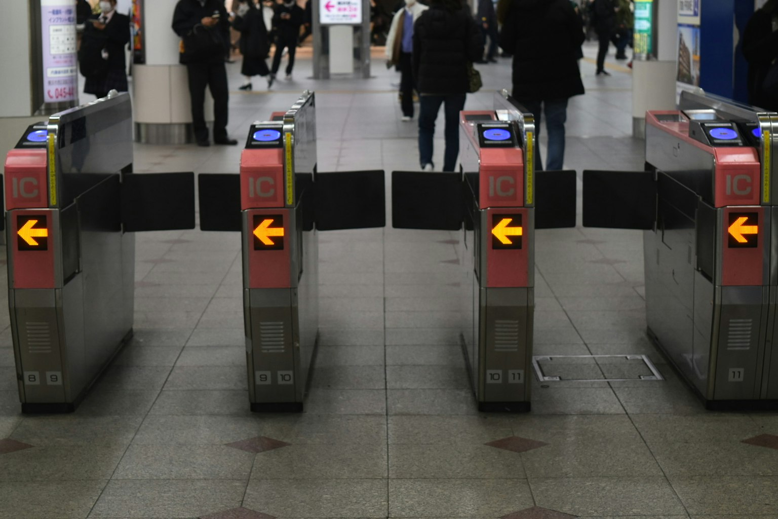 Vista dei tornelli in una stazione ferroviaria con persone che passano