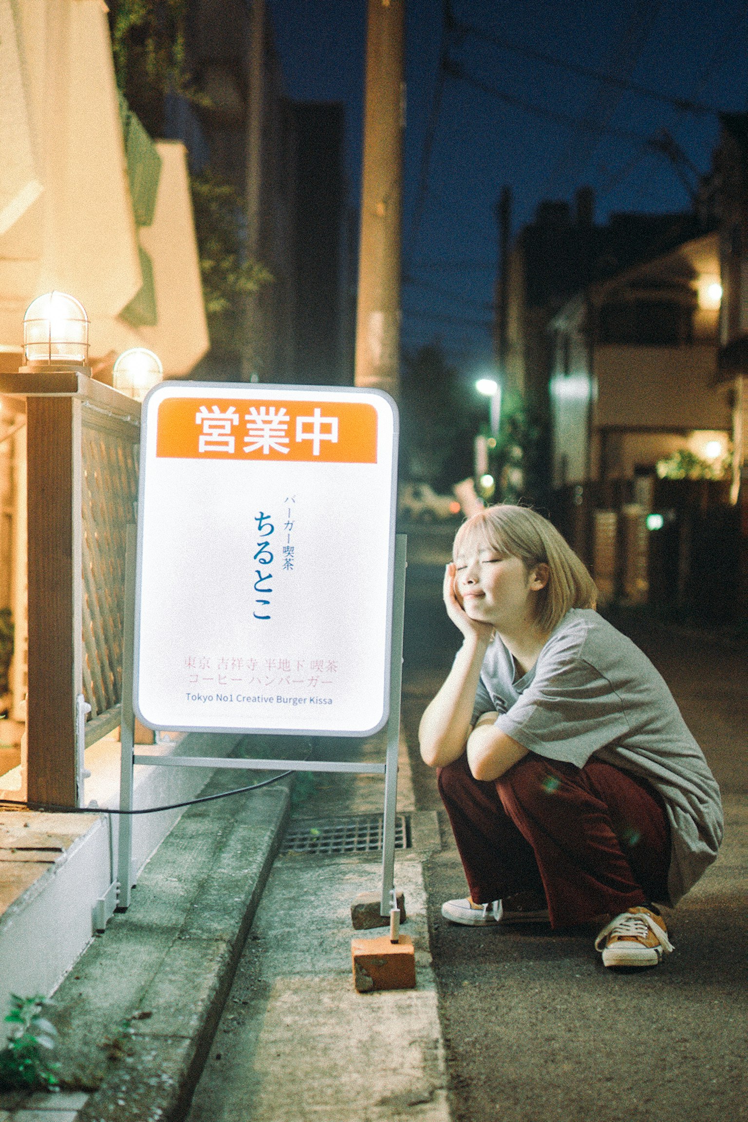 夜晚街头坐着的女性和明亮的招牌