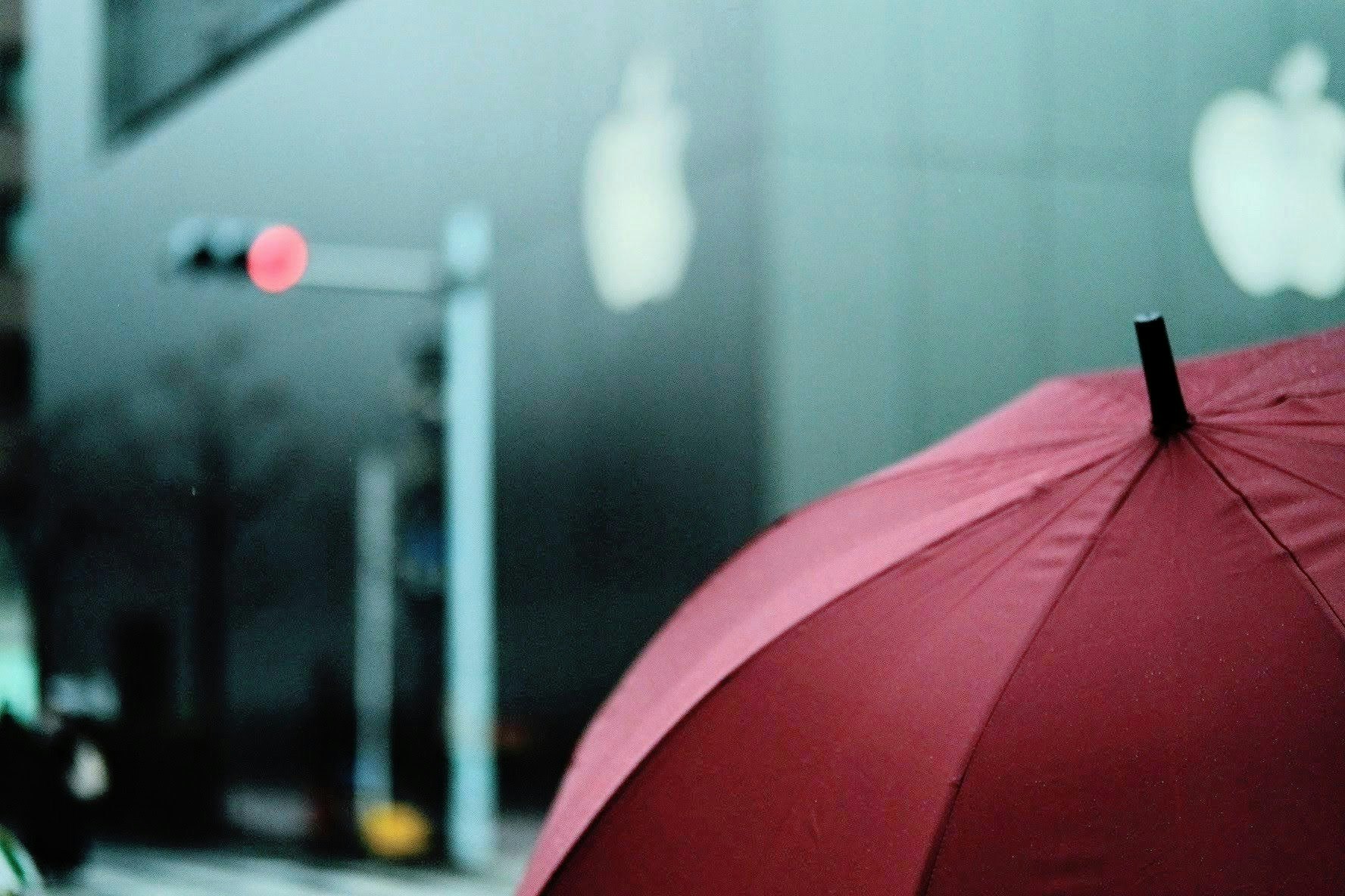 A red umbrella in the foreground on a rainy street