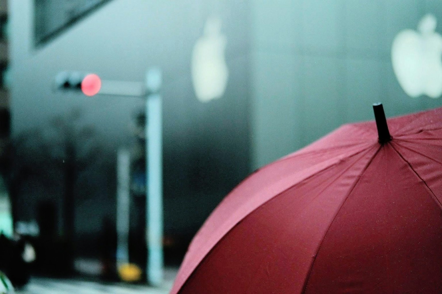 Red umbrella with Apple logos in the background on a city street