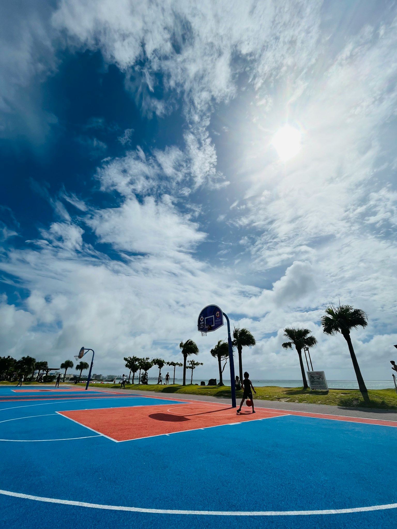 Heller blauer Basketballplatz unter einem teilweise bewölkten Himmel