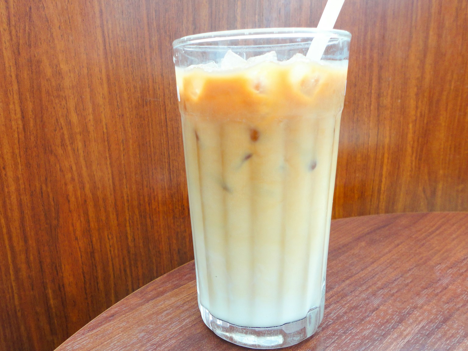 Bicchiere di tè freddo con cubetti di ghiaccio e una cannuccia