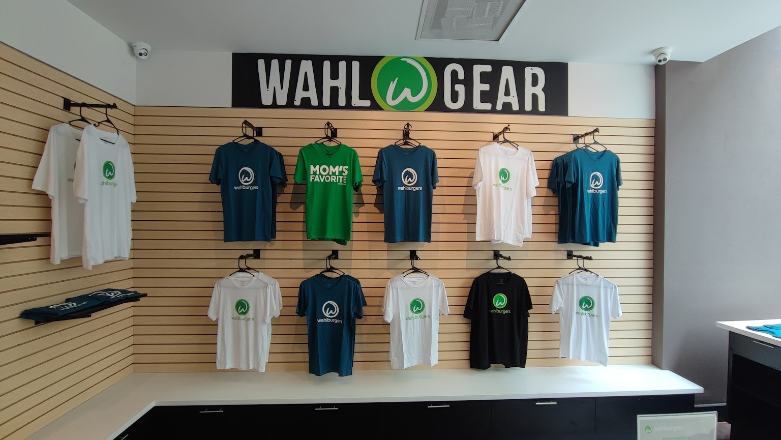 Esposizione di magliette Wahl Gear di vari colori su una parete