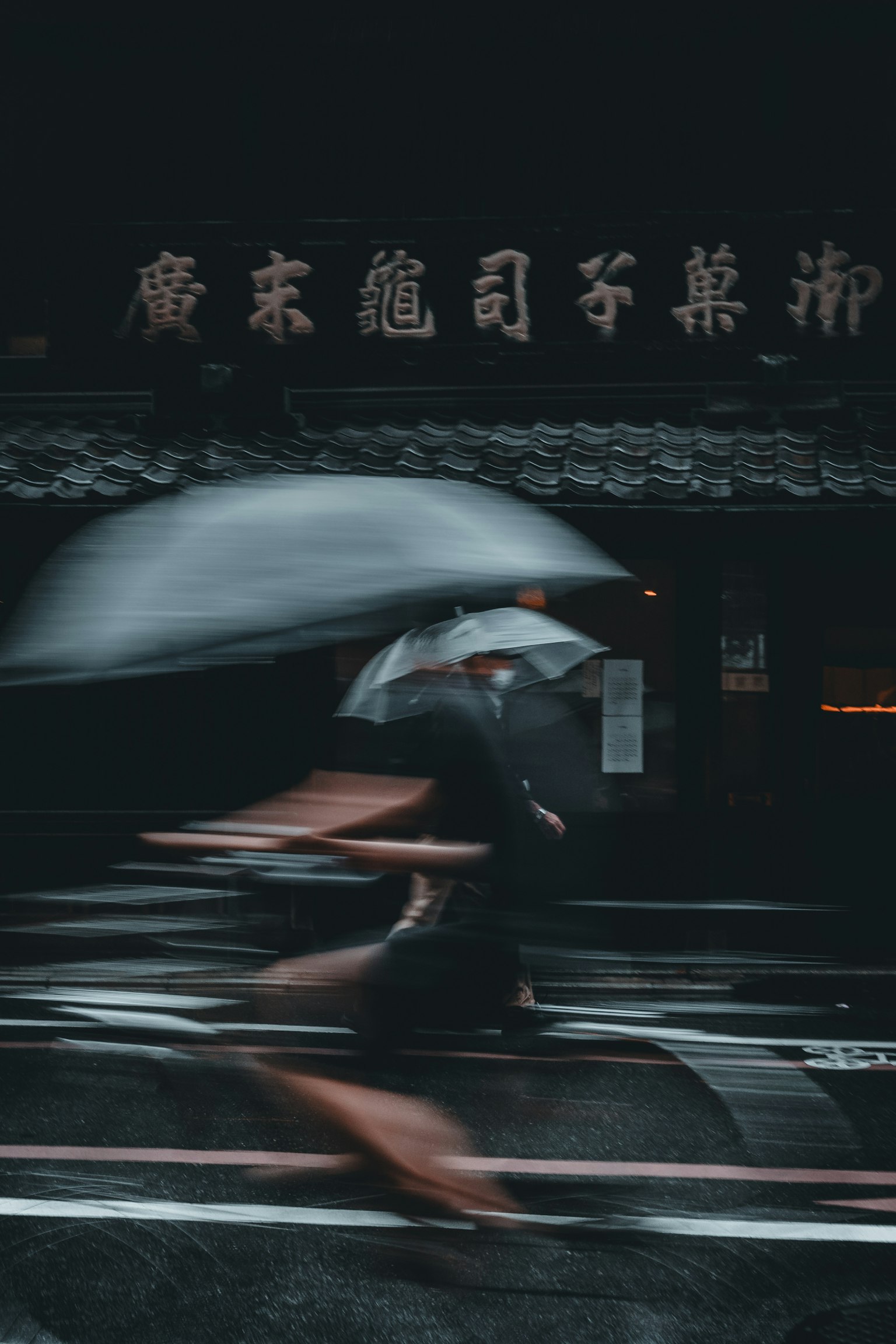 Hình ảnh mờ của một người đi bộ với ô dưới mưa Các ký tự Trung Quốc có thể nhìn thấy ở nền phía sau