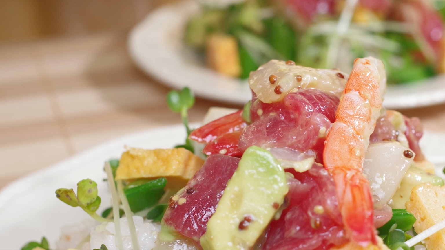 Colorful salad topped with fresh vegetables and sashimi