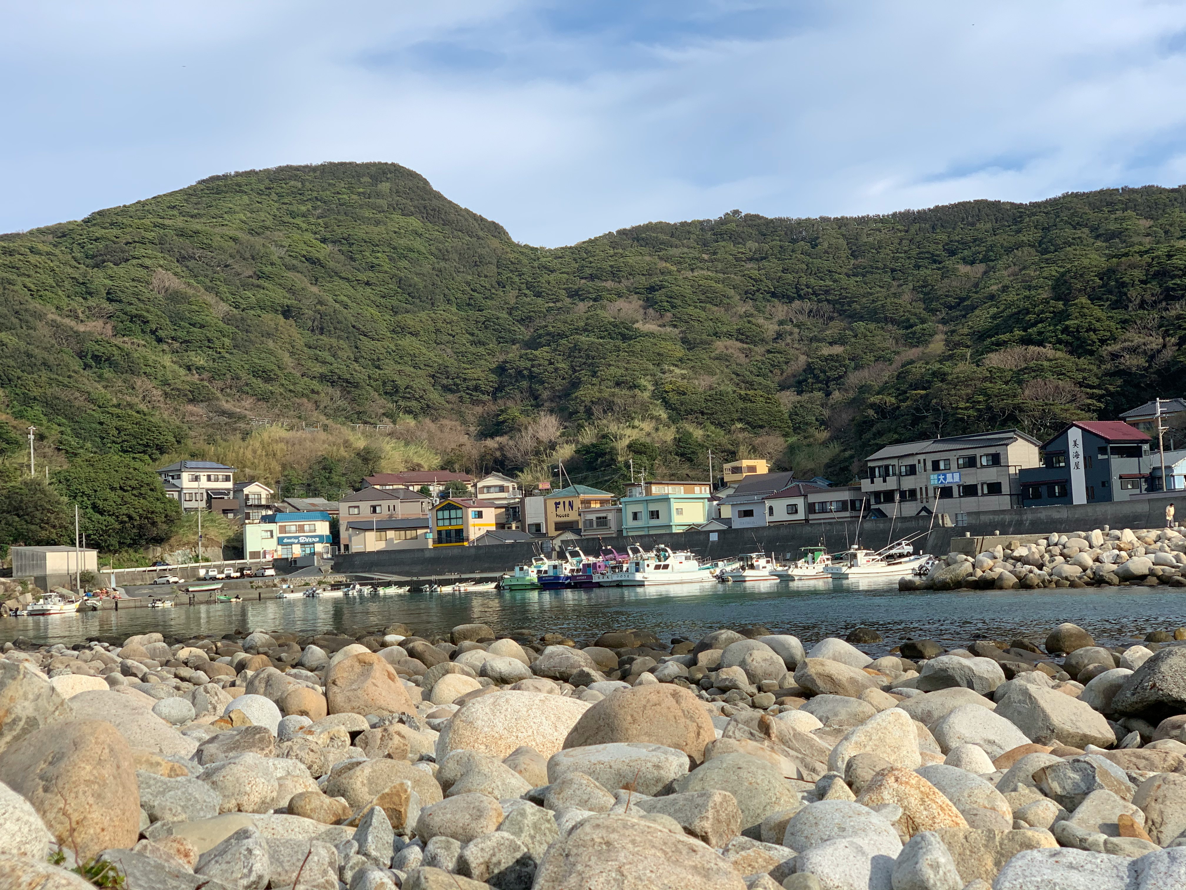 Costa rocciosa con diga del porto e montagne sullo sfondo