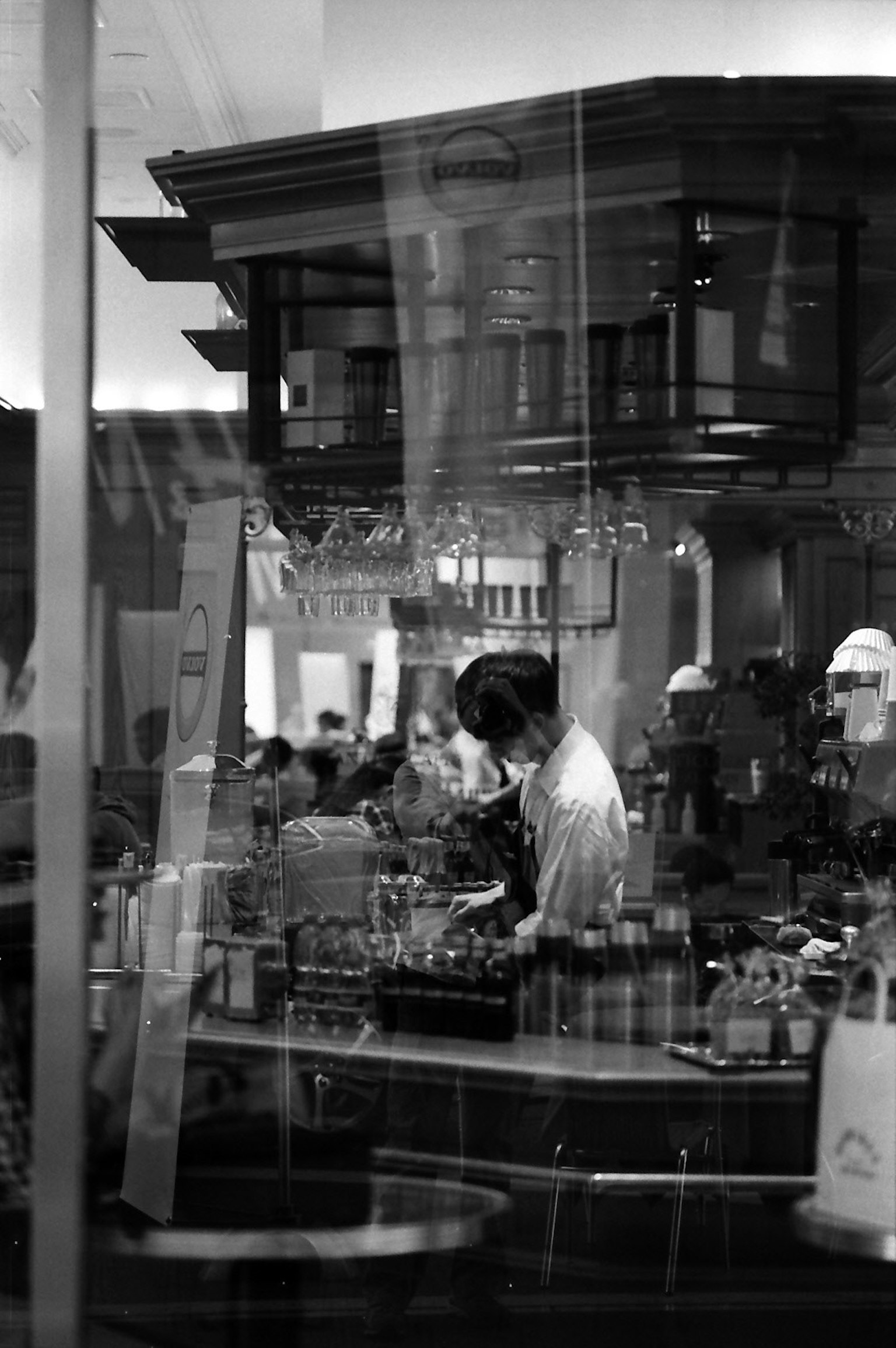 Foto in bianco e nero di un barista che lavora in un caffè affollato