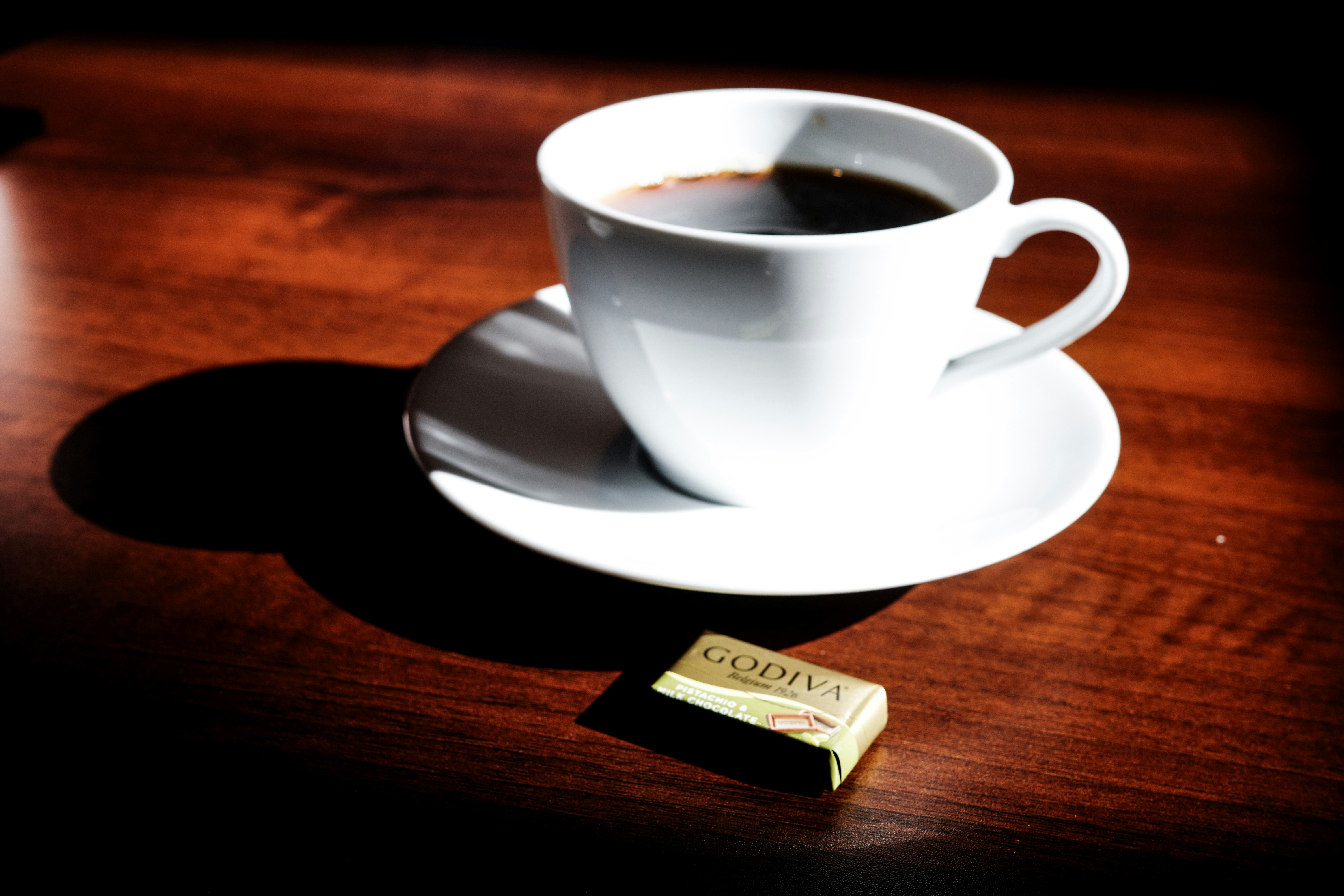 Kaffeetasse auf einem Holztisch mit einer kleinen Schokolade