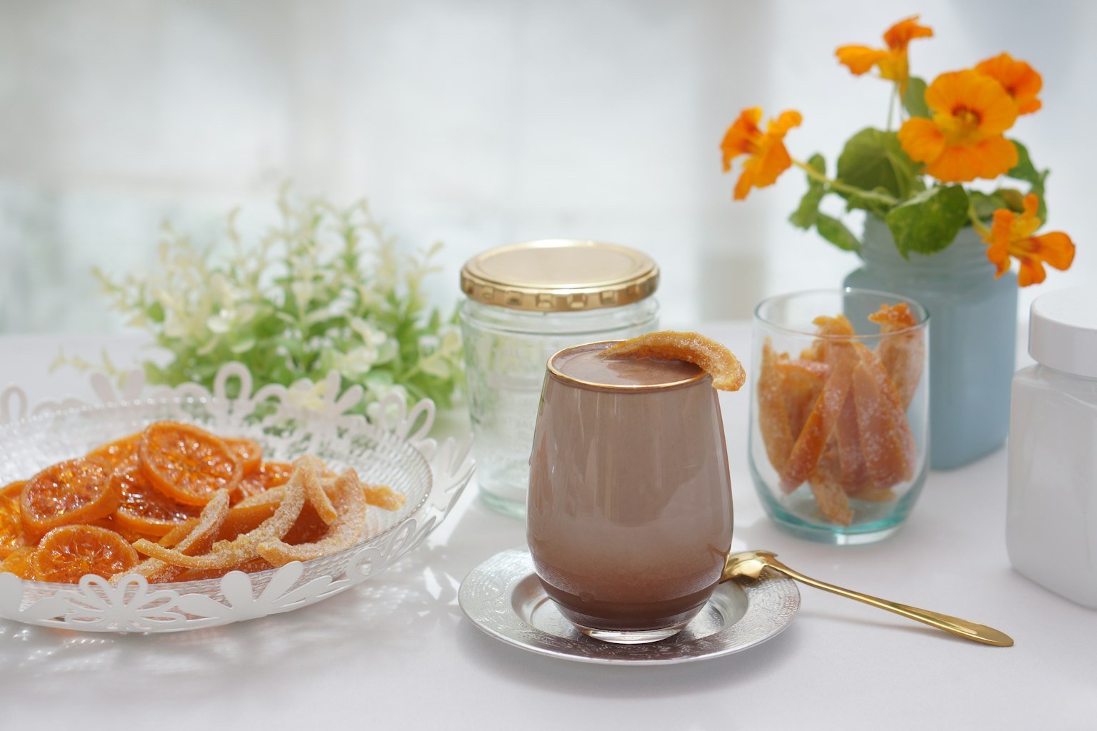 Ein schön gedeckter Tisch mit Schokoladendessert, kandierten Orangenscheiben und einer Blumenvase