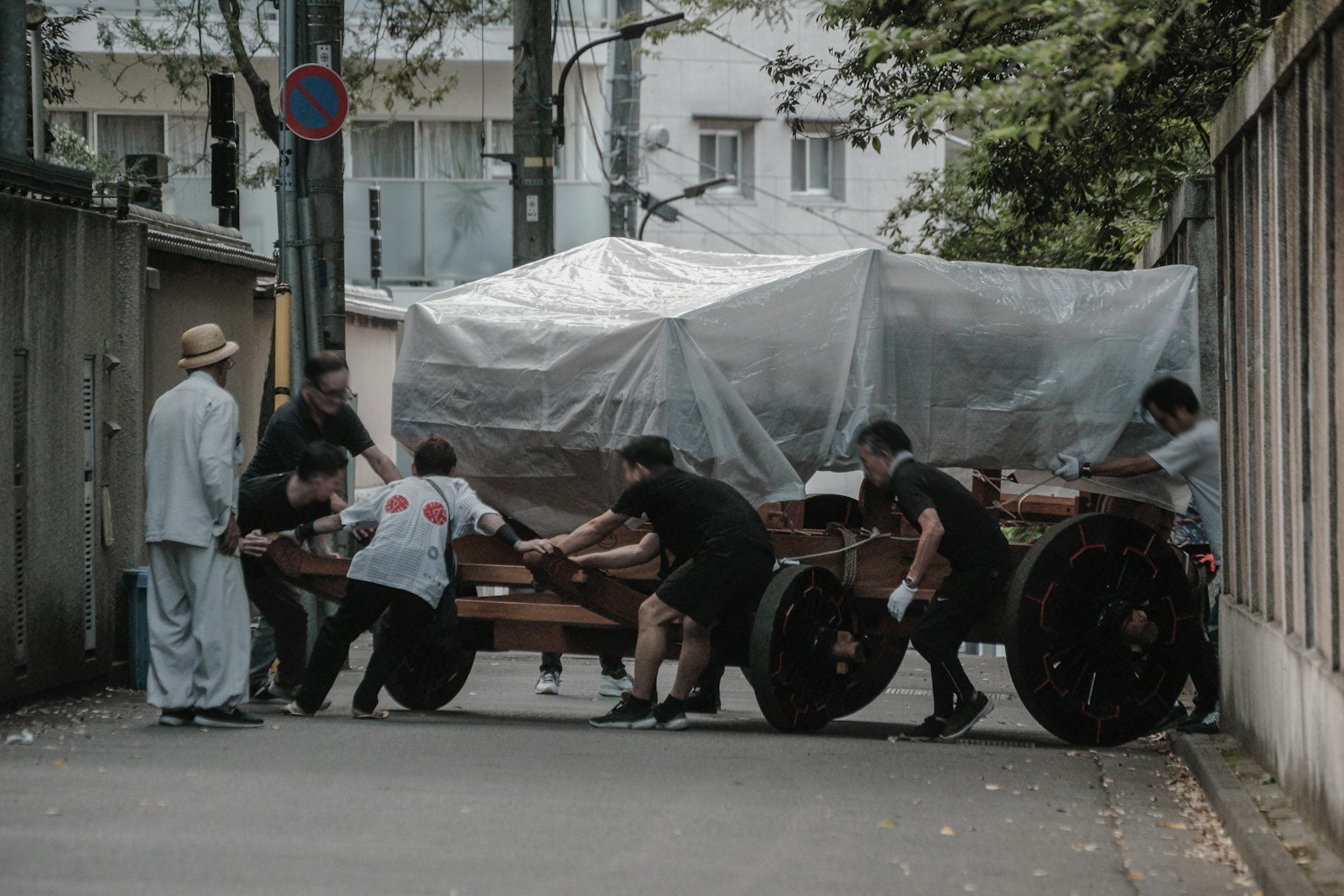 人们在狭窄的街道上推着木制手推车