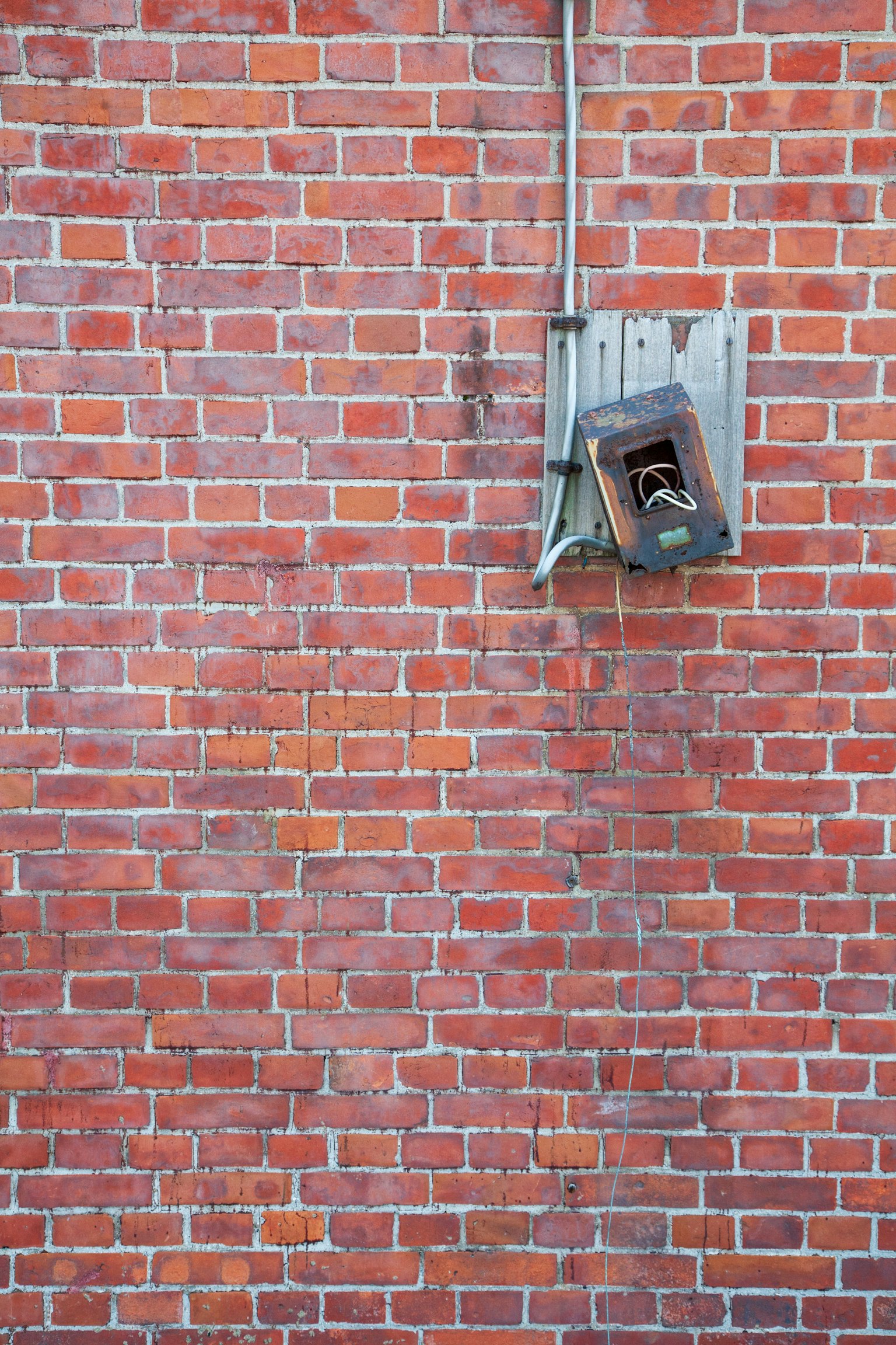 Image d'une vieille cabine téléphonique montée sur un mur en briques rouges