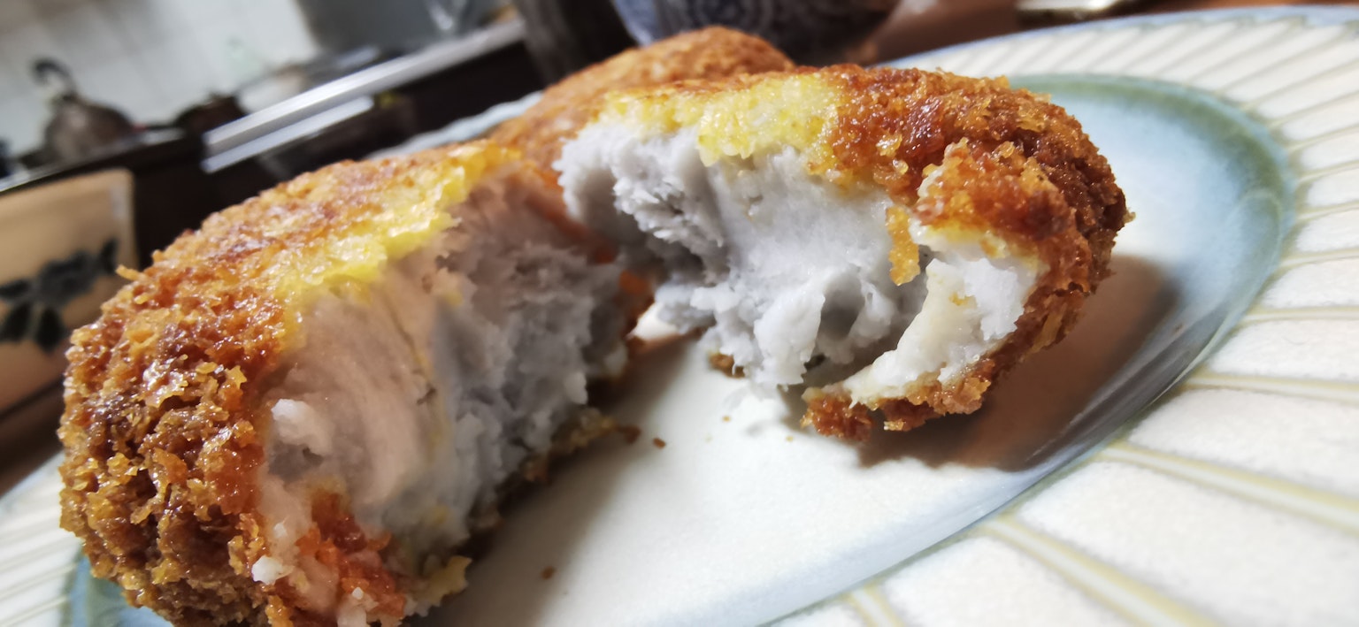 Sección de una croqueta frita que revela un relleno cremoso en el interior