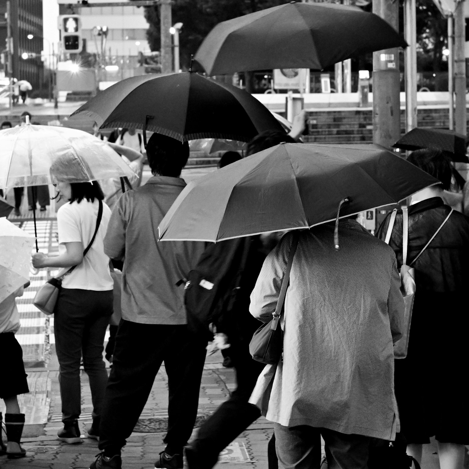 Schwarzweiß-Straßenszene mit Menschen, die Regenschirme halten