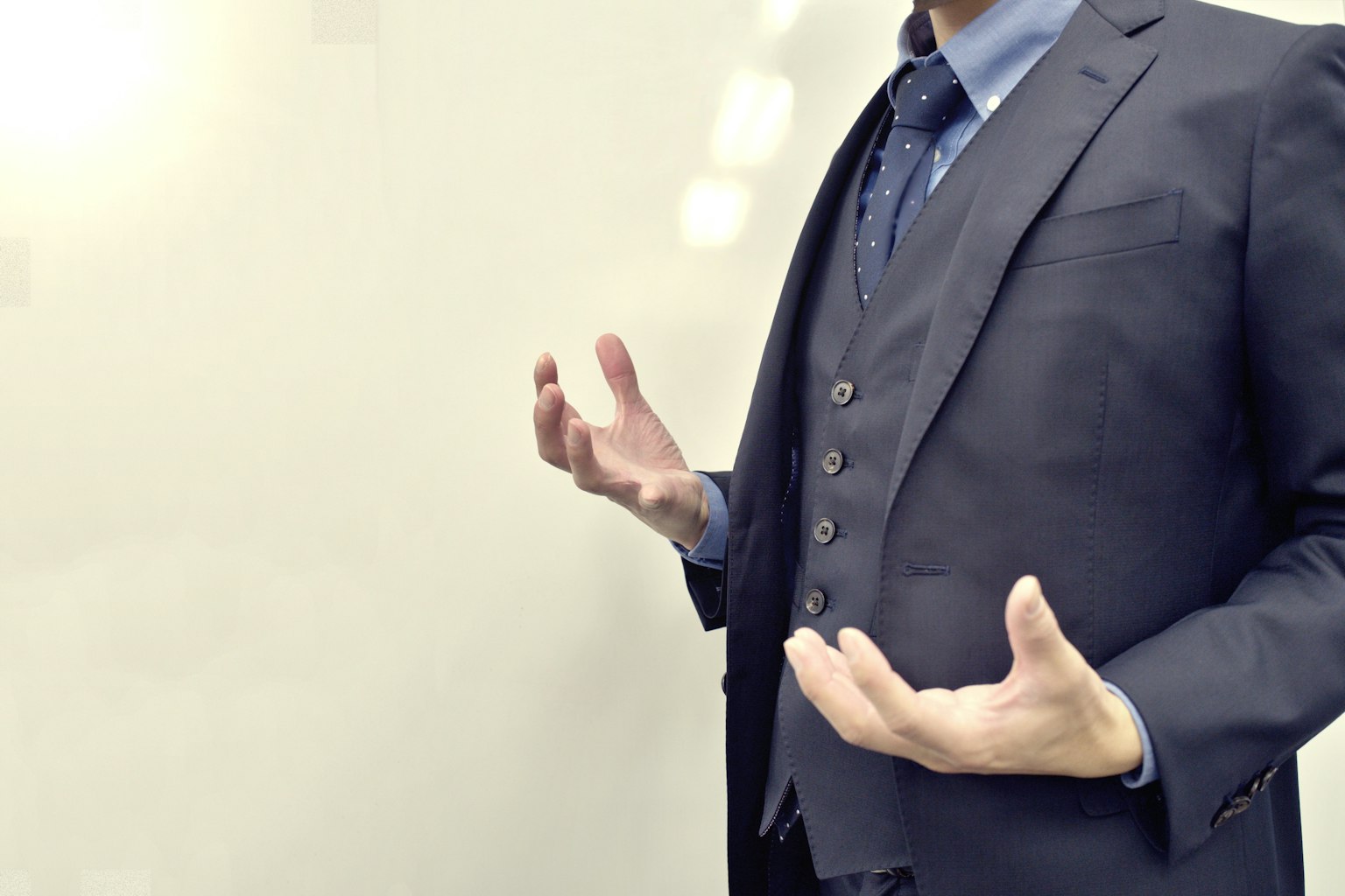 Un hombre en traje gesticulando con las manos abiertas