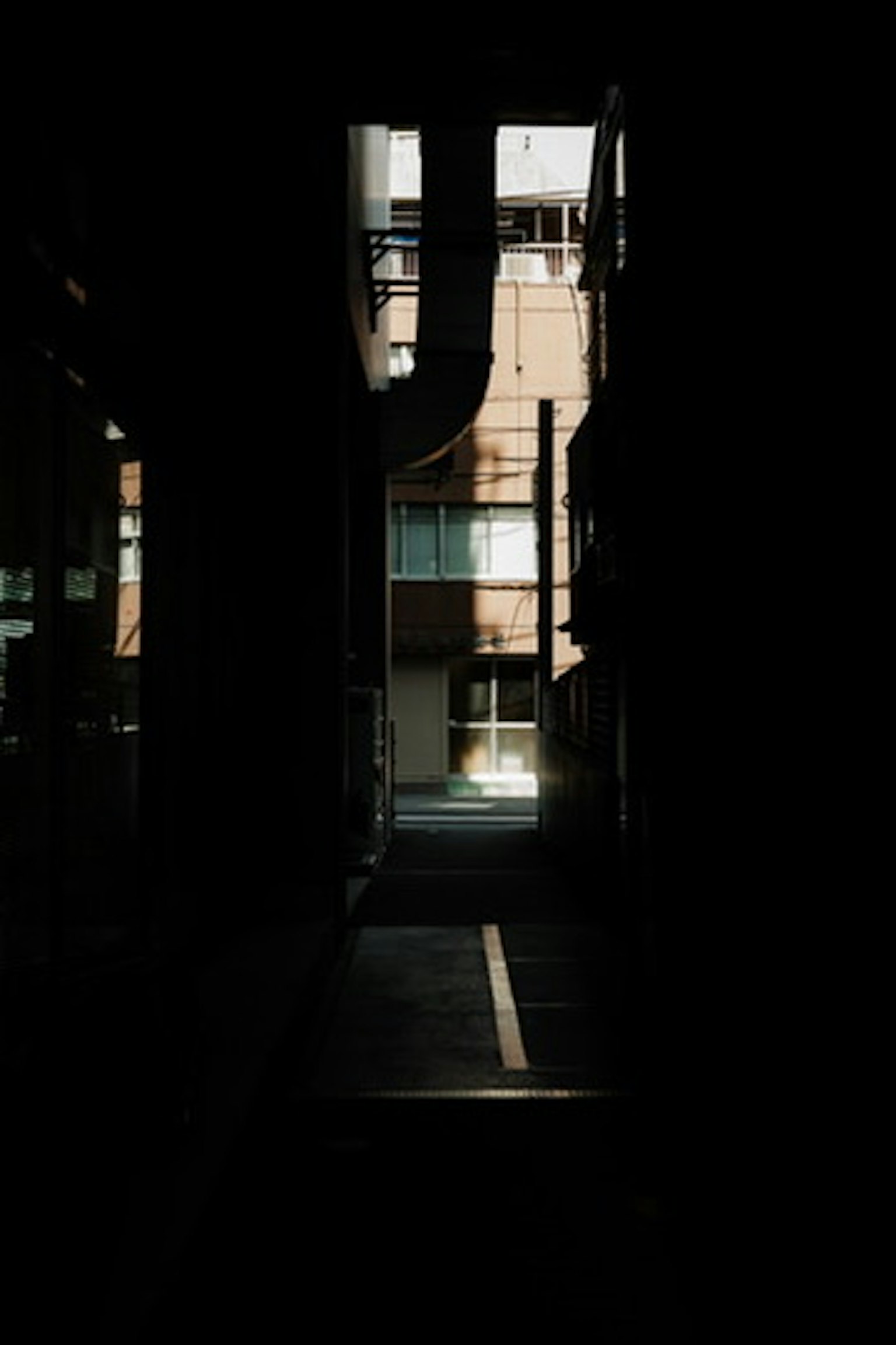 Callejón oscuro que conduce a una luz brillante con siluetas de edificios