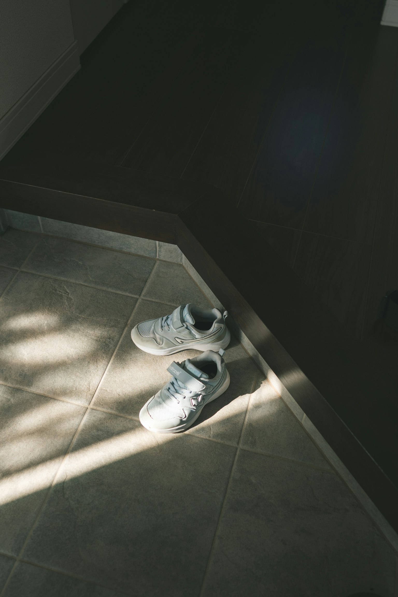 Chaussures placées sur un sol carrelé avec la lumière du soleil qui entre