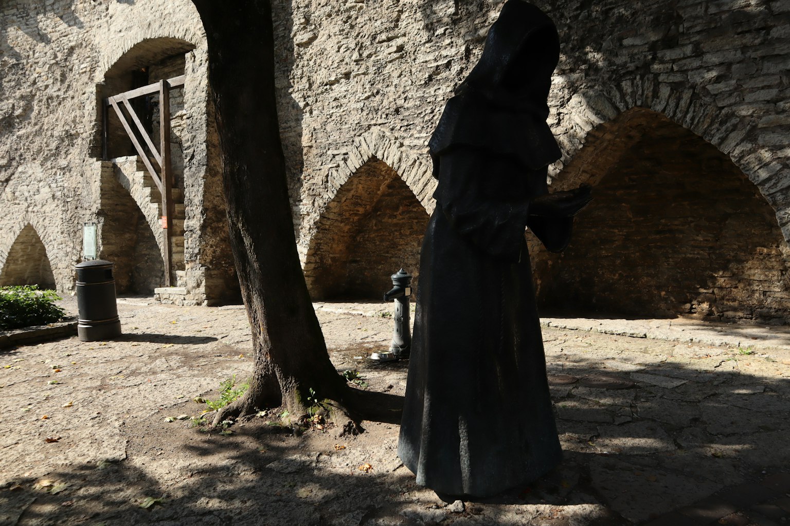 Silhouette d'une figure en robe noire se tenant près d'un mur en pierre