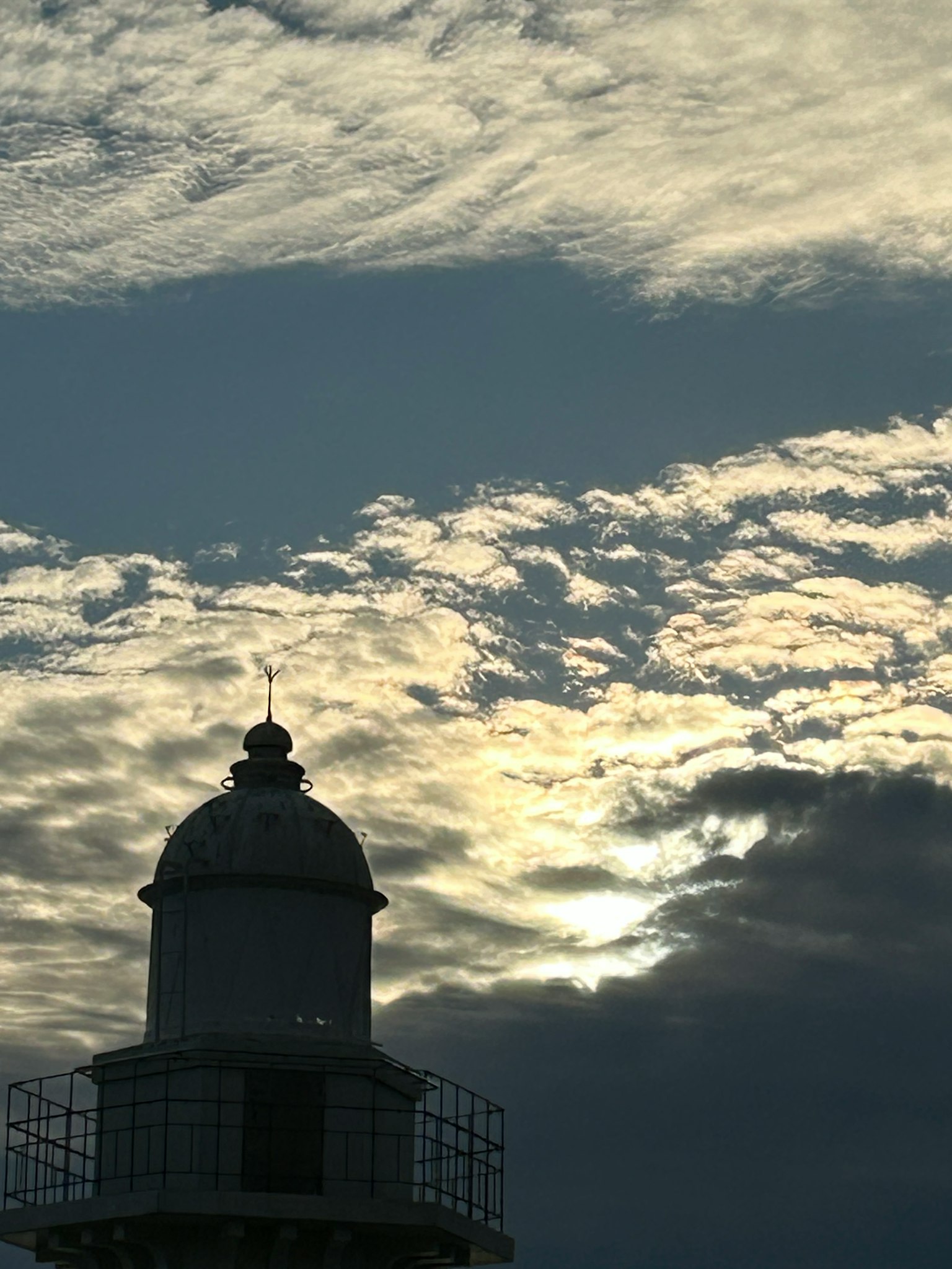 Faro silhouettato contro un cielo drammatico al tramonto
