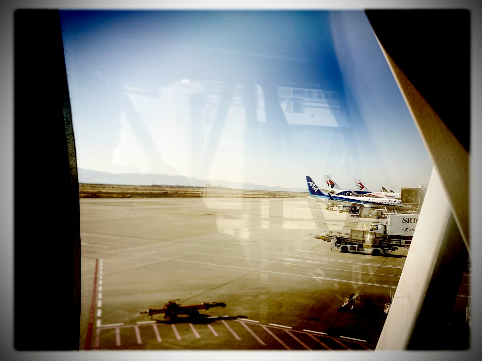 空港の窓から見える滑走路と飛行機の風景