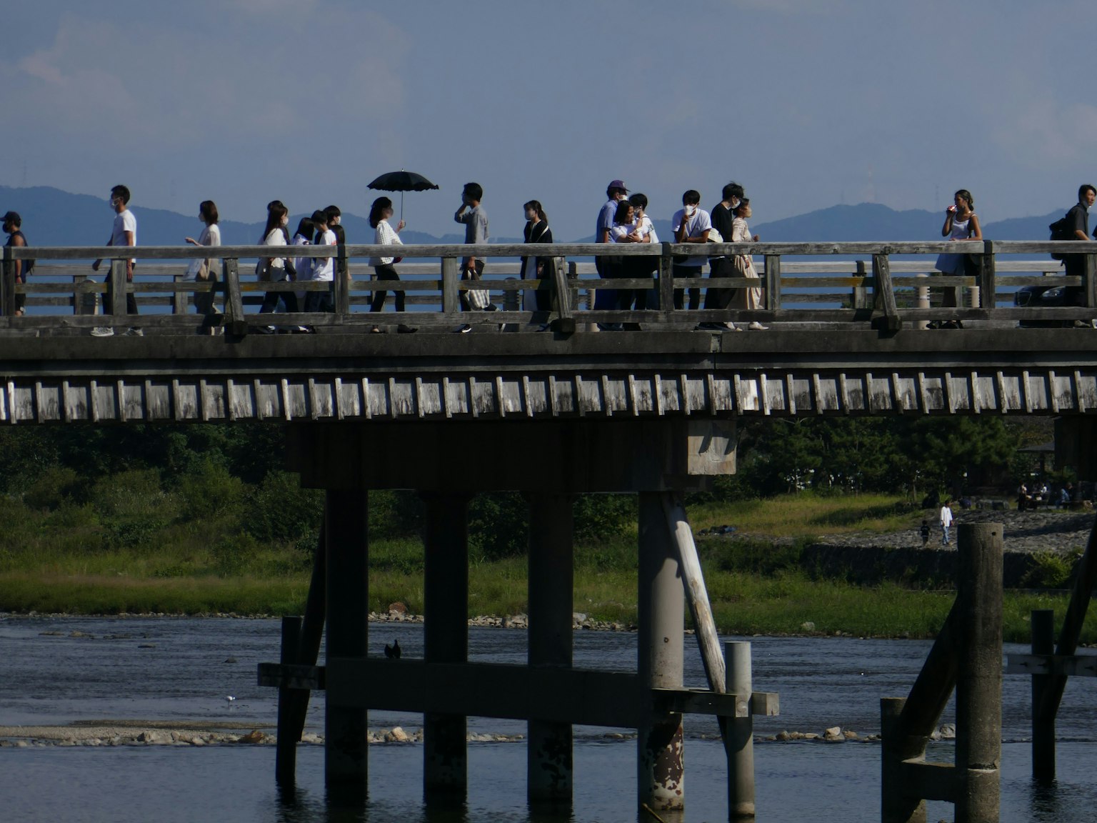People walking on a bridge under a blue sky